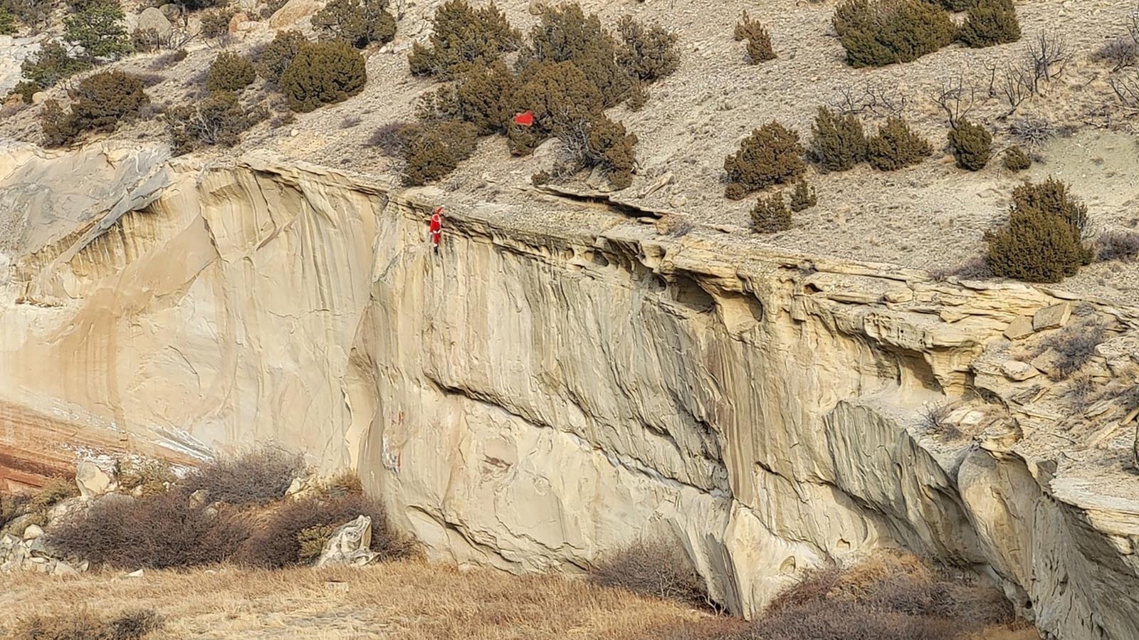 Santa dangles precariously from a cliff some where in Wyoming, prompting Fred Lowry to observe that "even the most experienced drivers can run into trouble in the Wyoming mountains!"