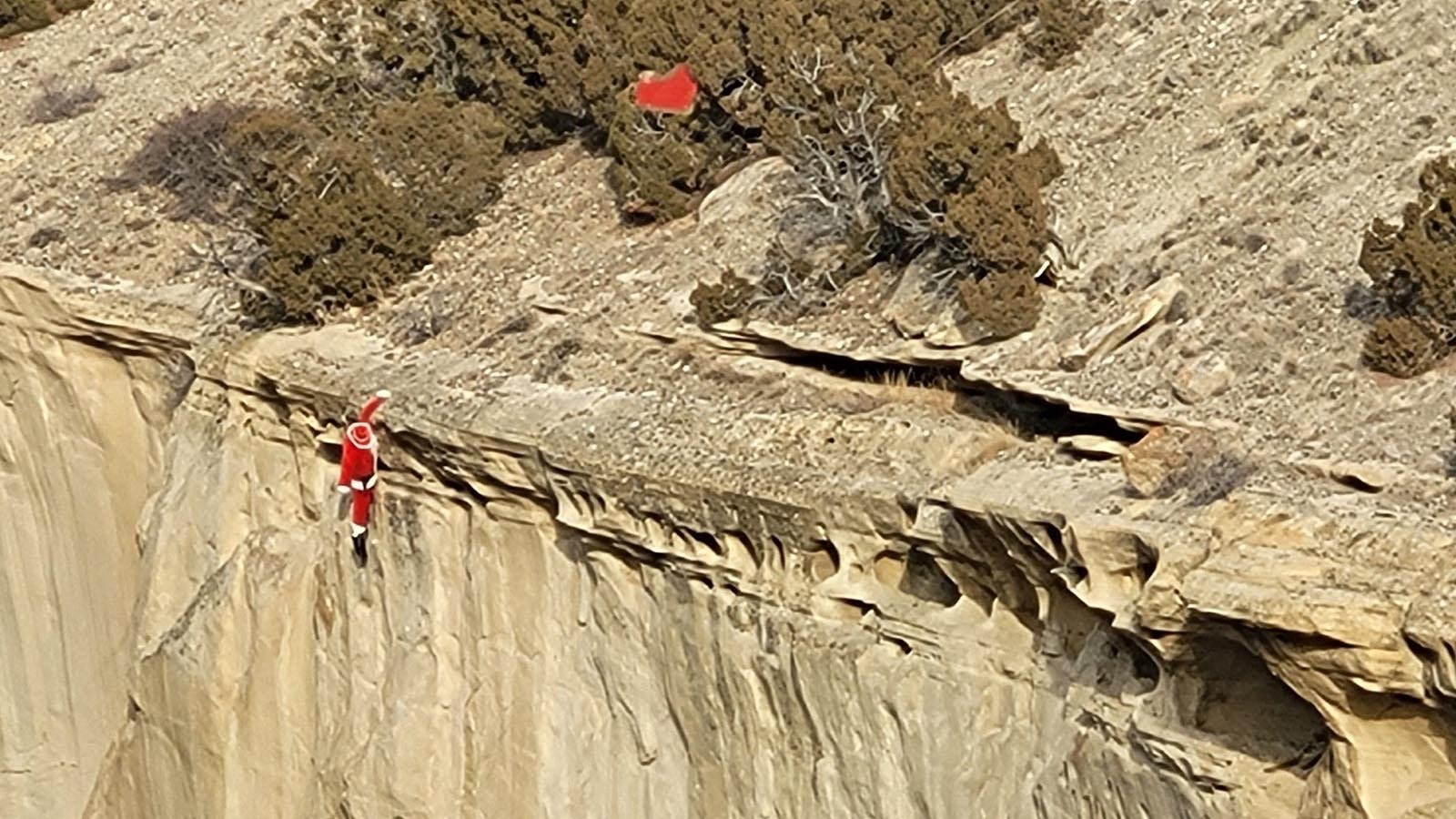 Santa dangles precariously from a cliff some where in Wyoming, prompting Fred Lowry to observe that "even the most experienced drivers can run into trouble in the Wyoming mountains!"