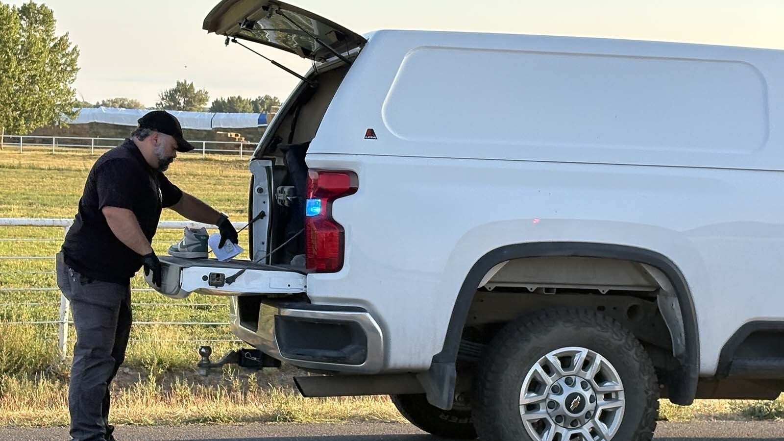 Fremont County Sheriff's Detective Anthony Armstrong places a white and teal, high-top sneaker style Nike shoe into an evidence bag, and into the back of an evidence truck.
