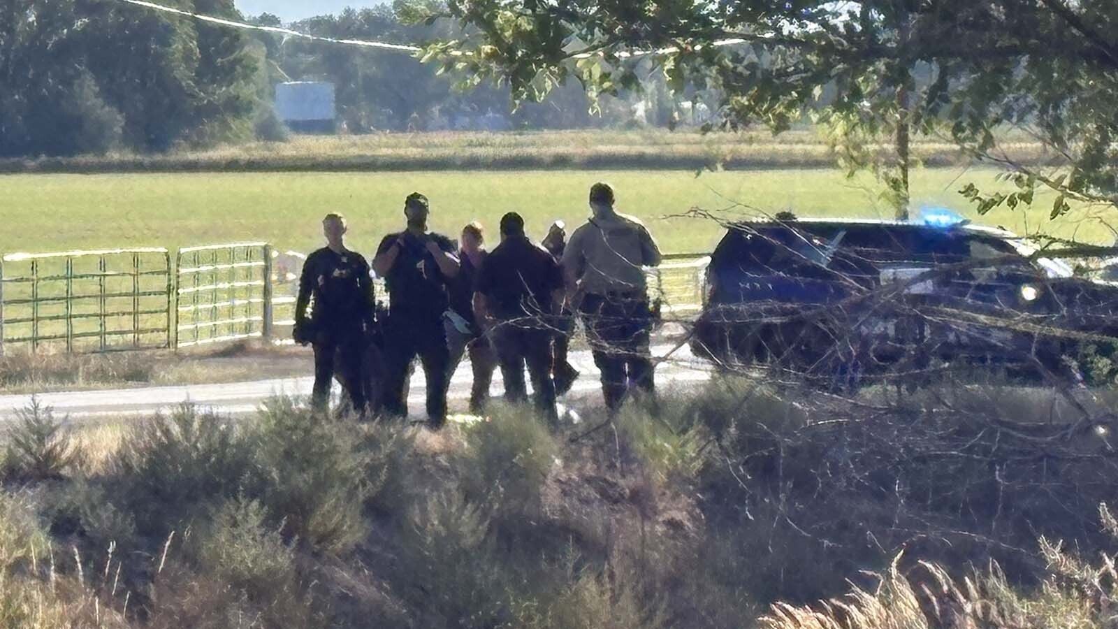 Riverton Police Department Officer Brandon Brookover and another officer stand in front of a body which lay on the ground Saturday morning, just before the Fremont County coroner's office took custody of it.