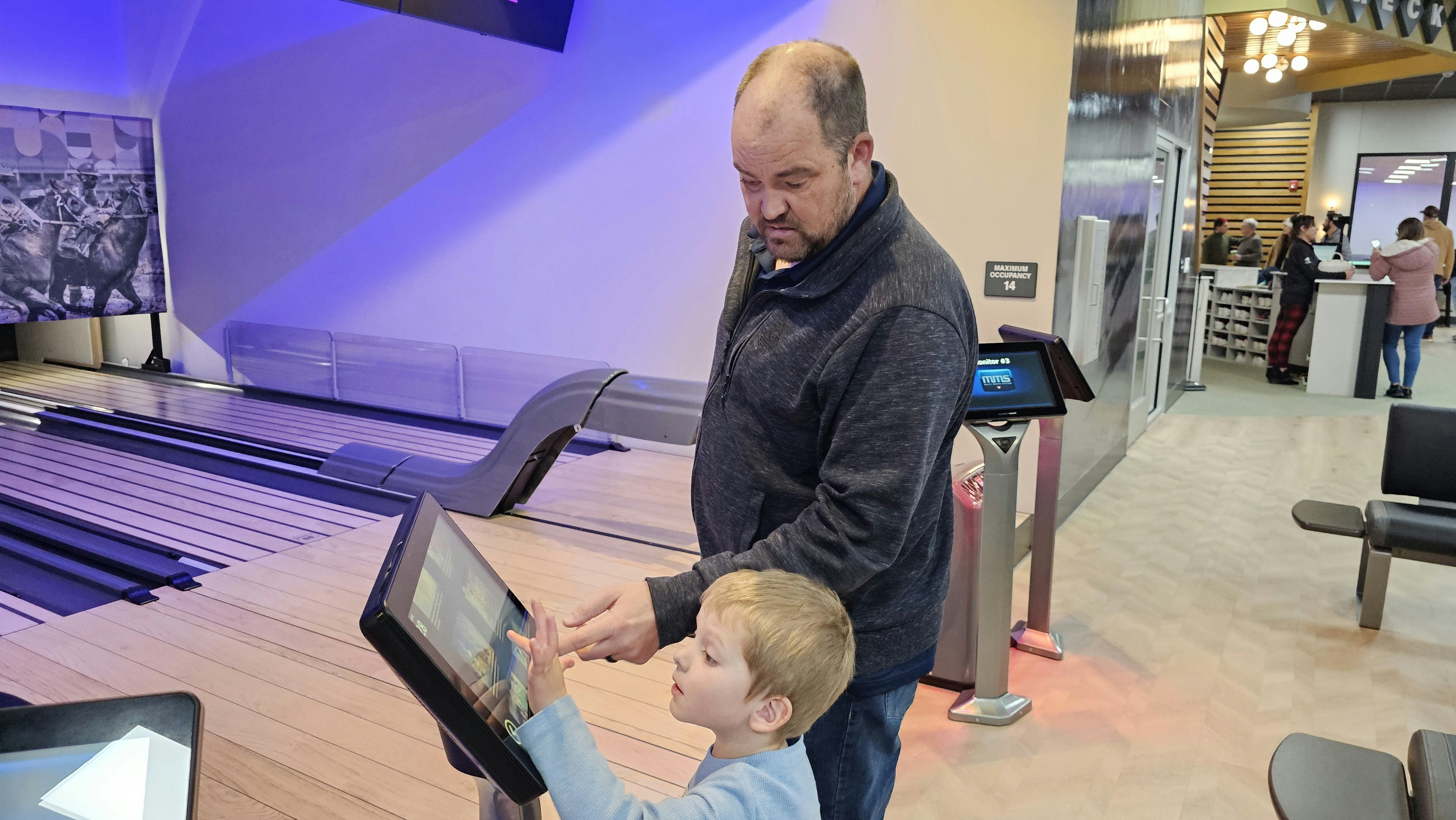 Bryan Goodman shows his son Cooper how the screen can be used to change parameters of a game of Pony Pins.