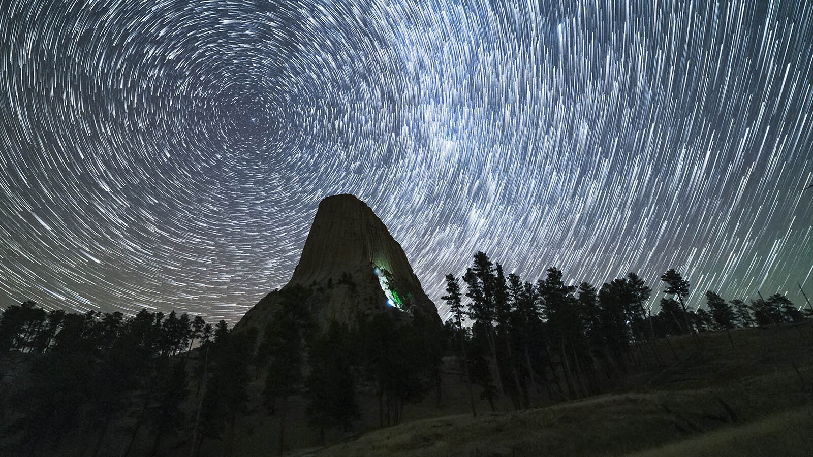 This time-lapse image shows the movement of the stars in the night sky over Devils Tower, and the light beacons worn by night climbers ascending it.