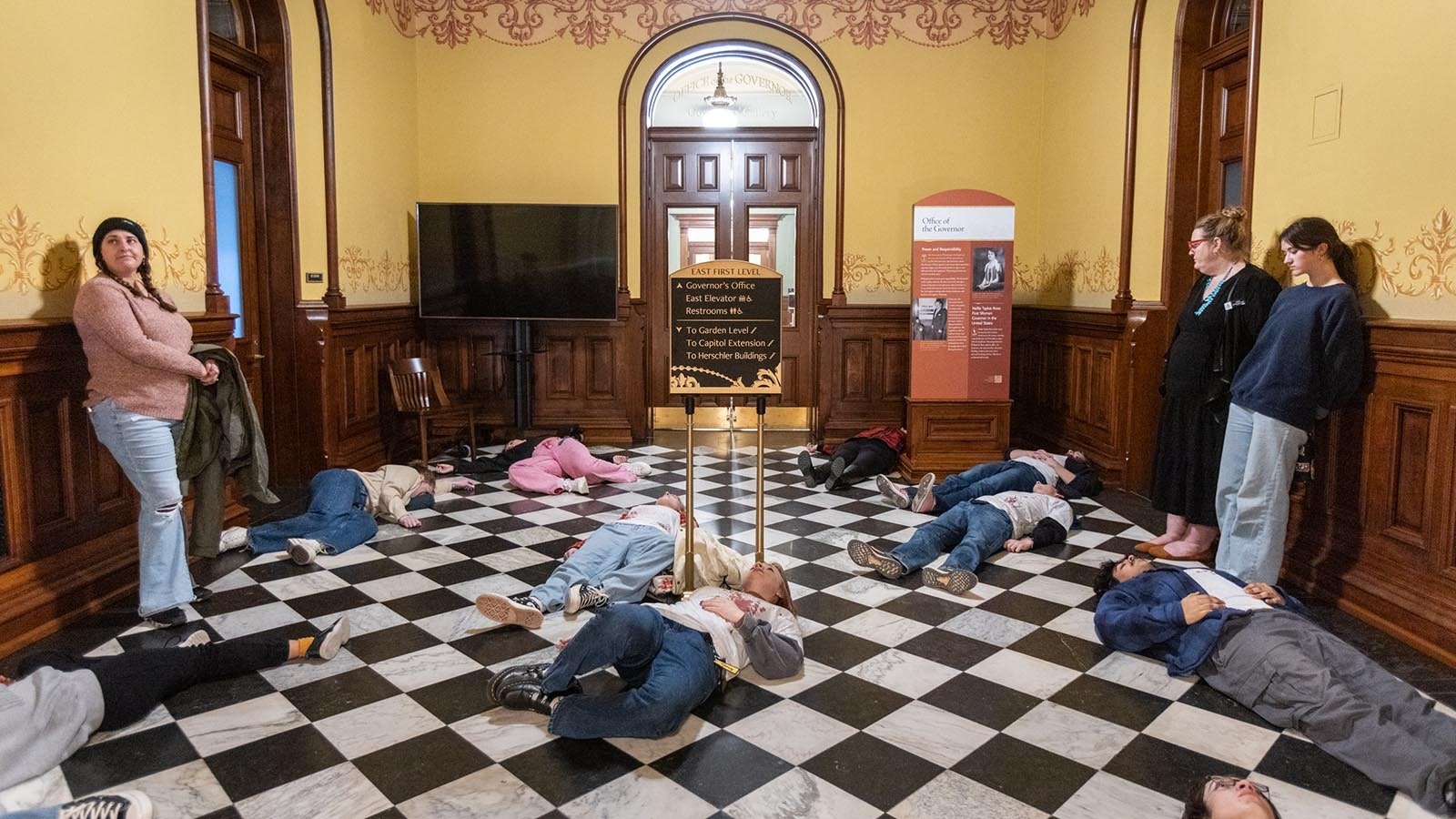 About 20 protesters made up to resemble shooting victims lay on the floor of the Wyoming Capitol on Monday afternoon, Feb. 24, 2025, over a bill that would ban gun-free zones.