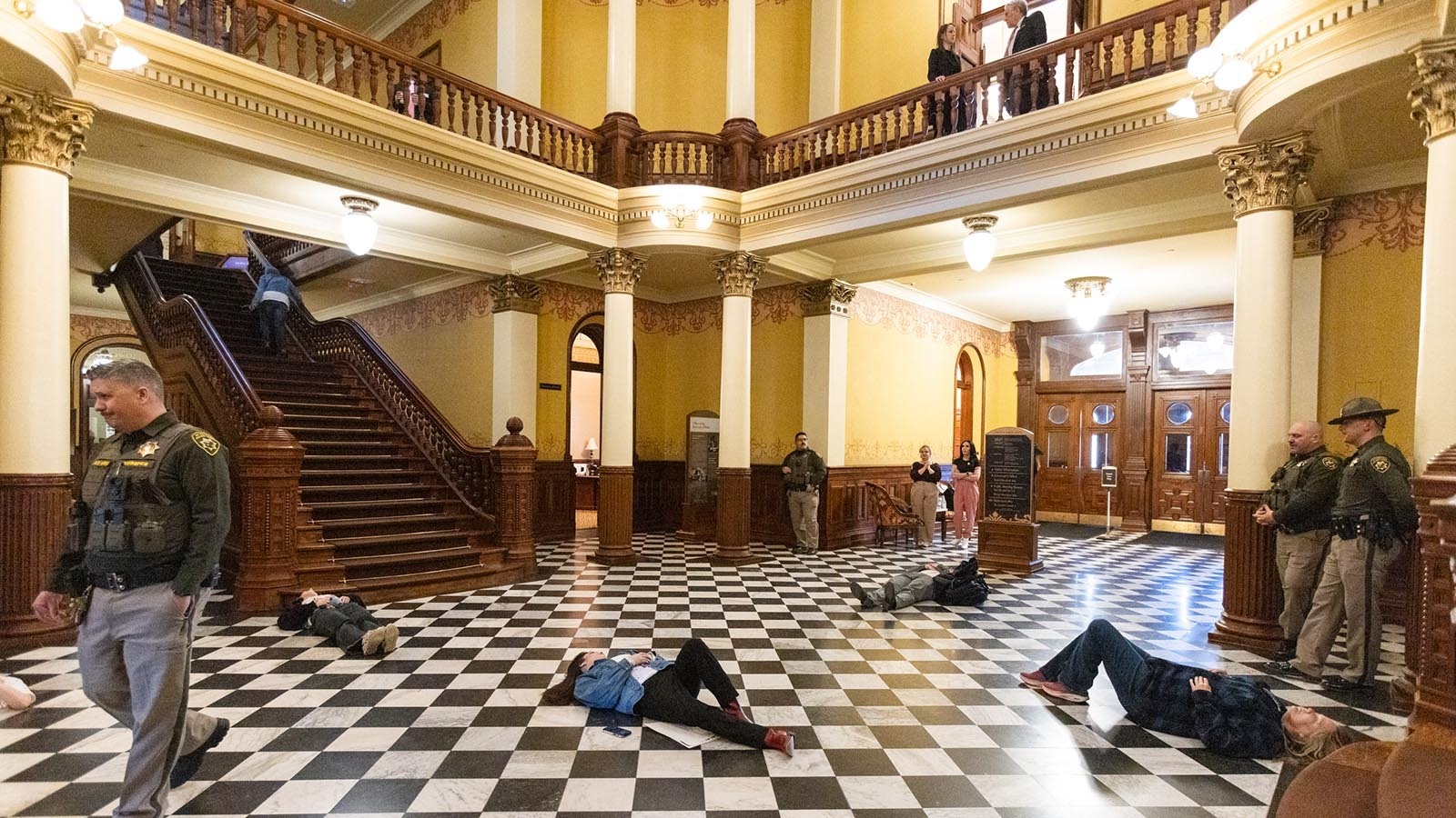 About 20 protesters made up to resemble shooting victims lay on the floor of the Wyoming Capitol on Monday afternoon, Feb. 24, 2025, over a bill that would ban gun-free zones.