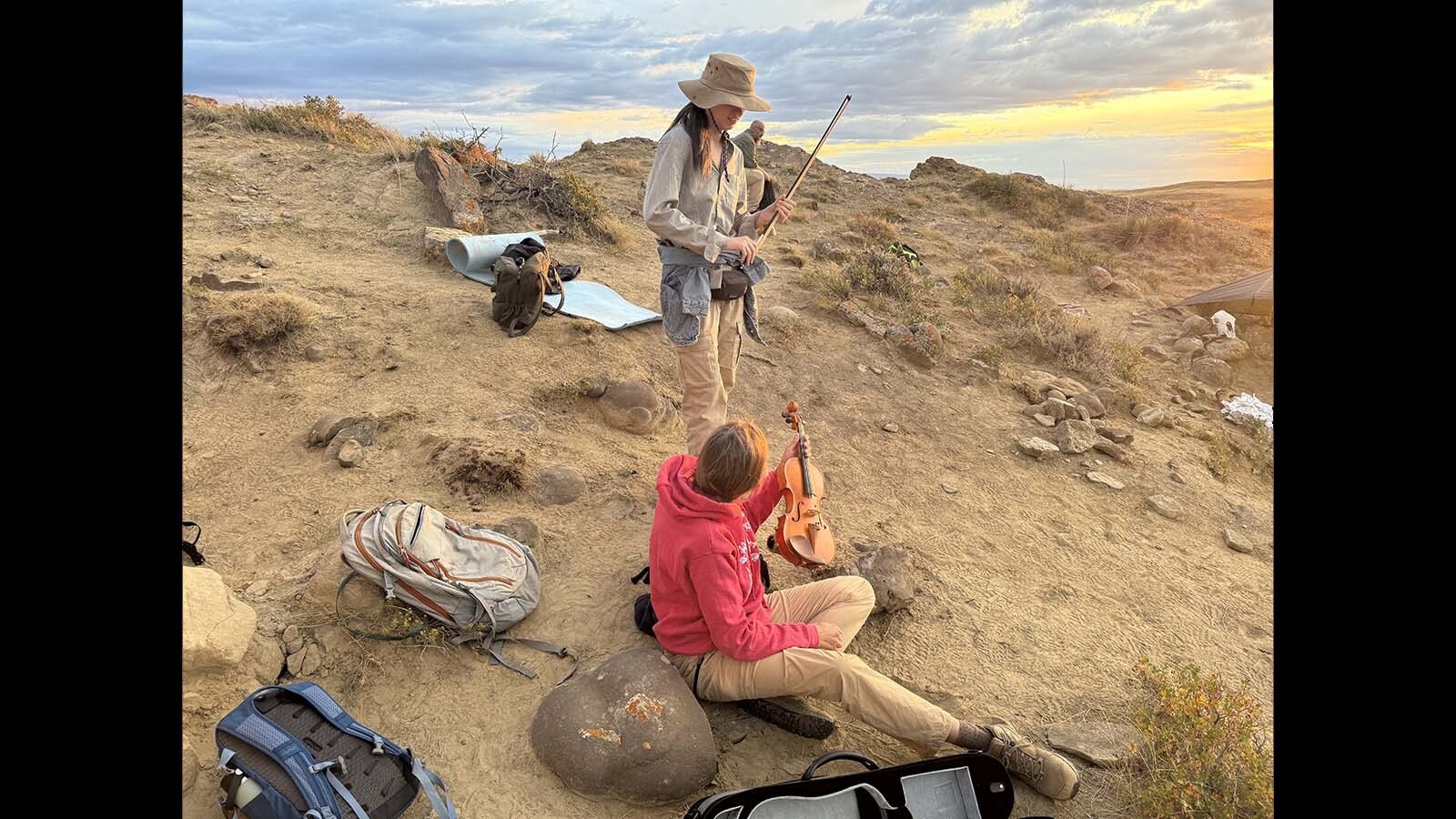 Amy Toth, an entomologist from Iowa, hands her custom-built family violin to professional musician Alanna North during the "dig by dark" at Triceratops Gulch near Glenrock.