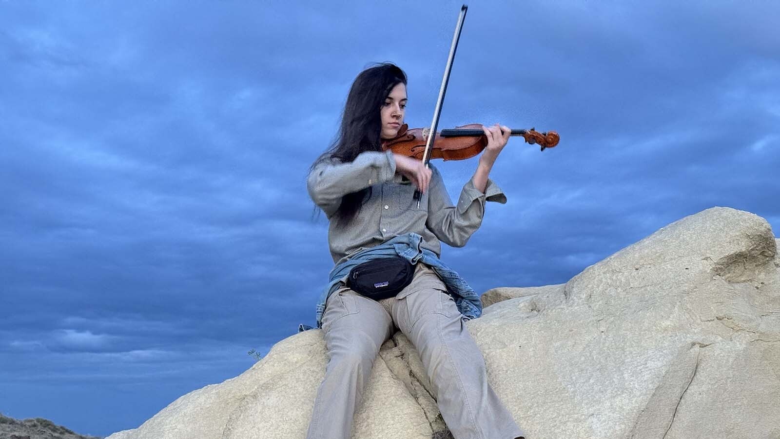 Professional musician Alanna North performs atop a large sandstone boulder at Triceratops Gulch near Glenrock. This was North's first dinosaur excavation and first visit to Wyoming, showcasing her unique talents while fulfilling her lifelong dream to dig for dinosaur fossils.