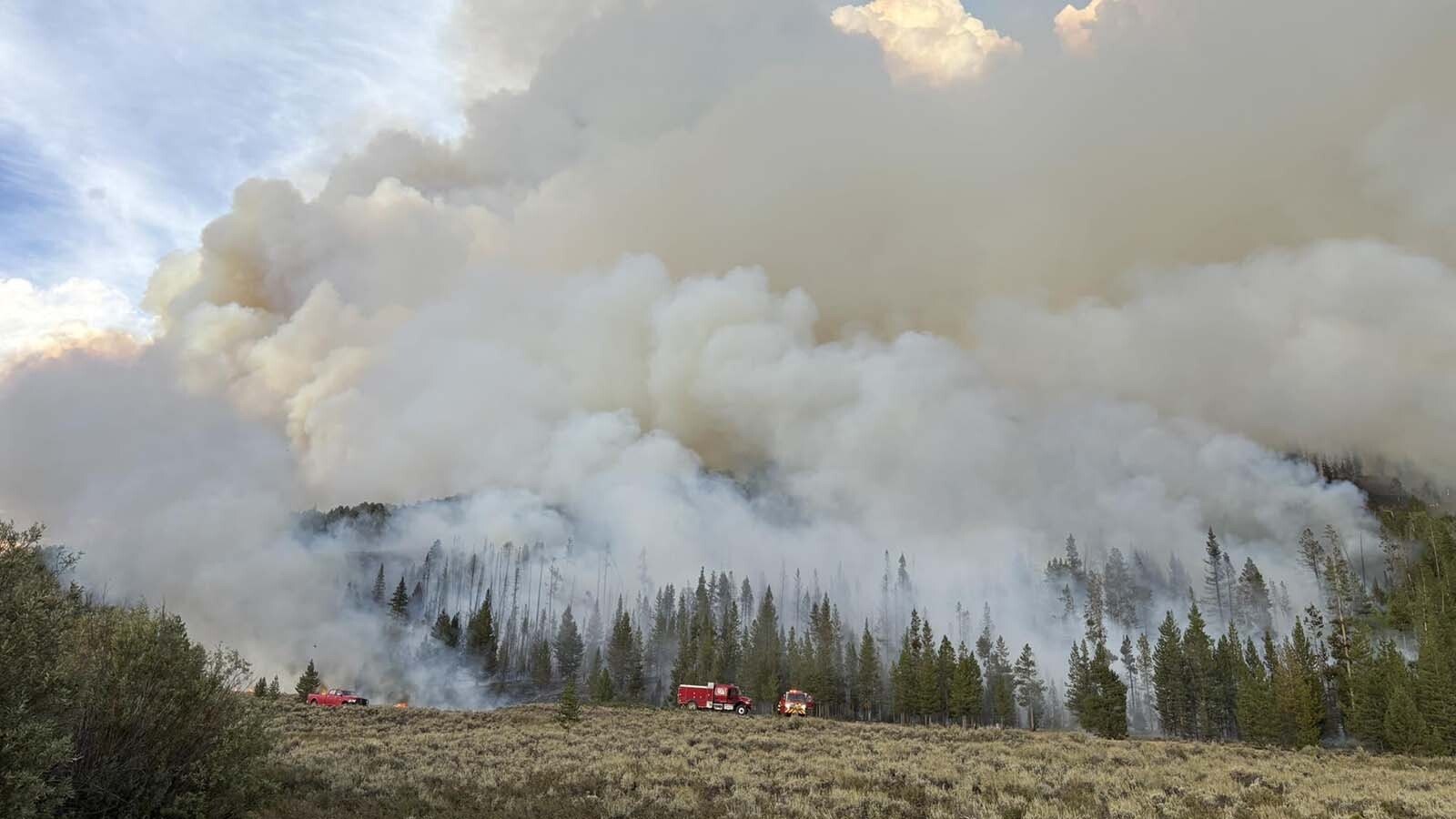Firefighting crews working a pair of uncontained wildfires in western Wyoming can expect some help from Mother Nature this week. Unseasonably cool, humid and wet weather will park over the fires through Friday. This image shows volumes of smoke rising from the Dollar Lake Fire.
