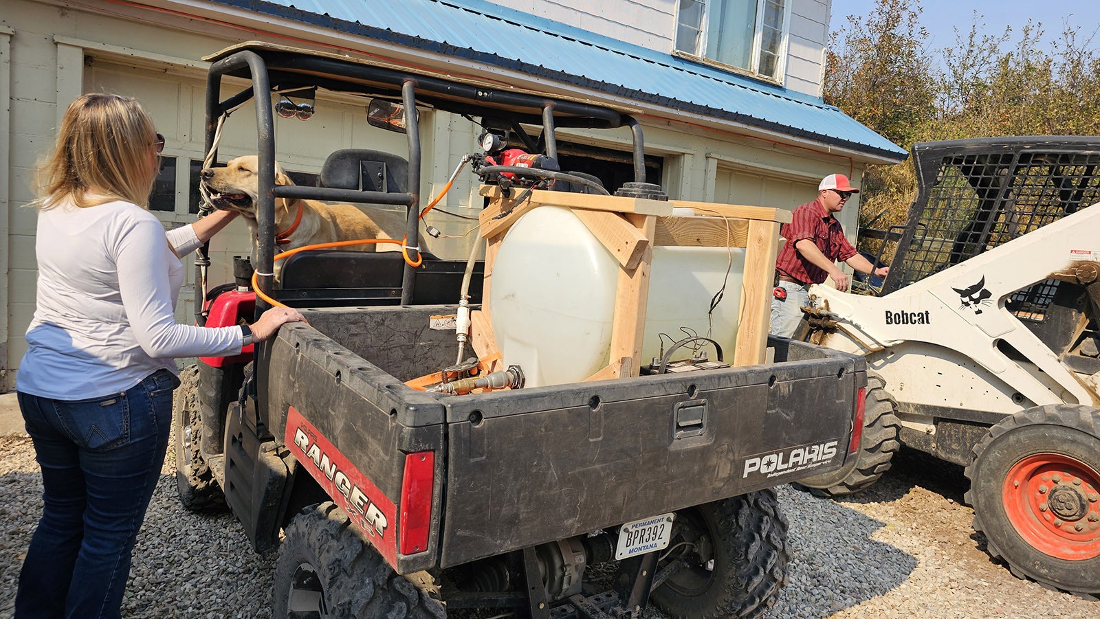 Chelsie Warner scratches one of her dogs under the chin before booting him out of this ATV, set up with a 70-gallon water tank to put out spot fires around the Double Rafter Ranch north of Parkman, Wyoming.