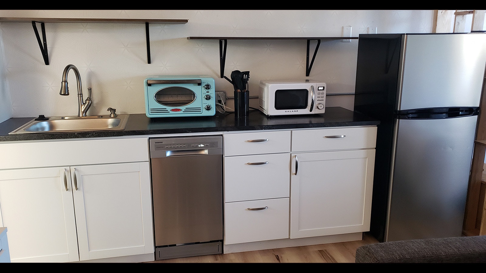 The kitchenettes include a colorful toaster and a microwave, as well as a small dishwasher, a refrigerator, a sink and cabinet space.