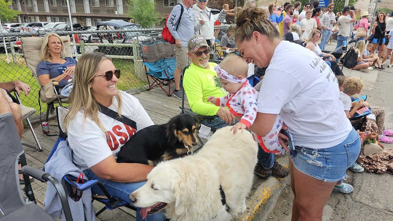 Kaisley Dow pets a white dog named Maverick, while her grandmother, Jami Dow holds her. The dogs belong to Colleen, left, and Randy Cargo, looking on in the bright yellow shirt.