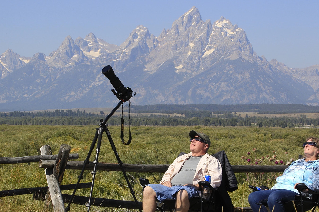 A couple views the solar eclipse in the first phase of a total eclipse in Grand Teton National Park on Aug. 21, 2017, outside Jackson, Wyoming. Tens of thousands of people flooded into the Cowboy State to view the total solar eclipse, which was at its peak across Wyoming.