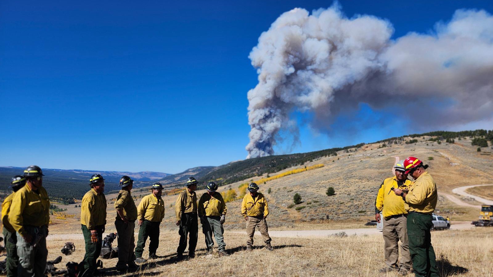 A fire crew maps out a plan of attack as a column of smoke rises from the Elk Fire in northern Wyoming.