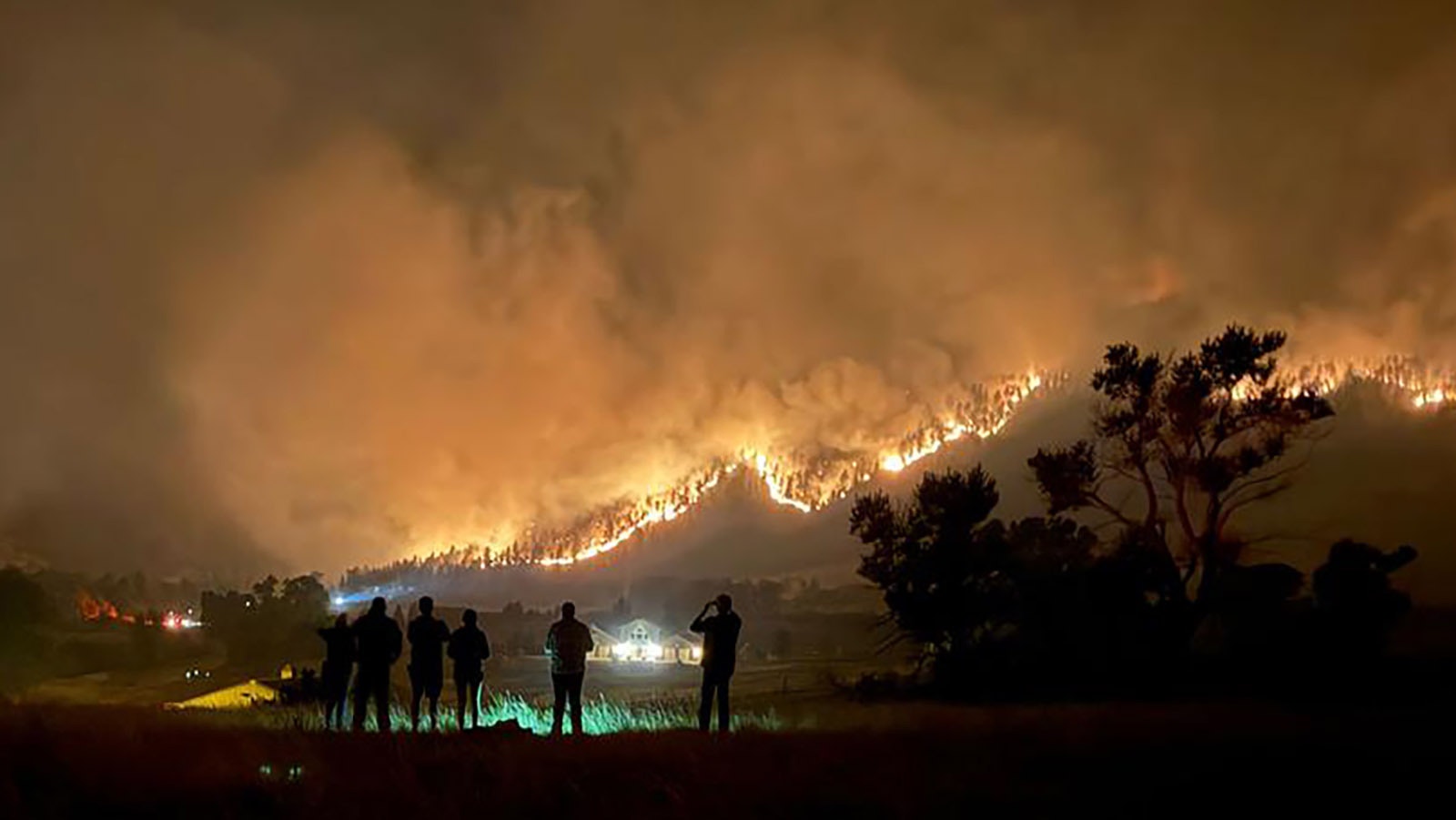 A group of people watch as a ribbon of fire burns it way across the face of the Bighorns near Dayton and Parkman, Wyoming.