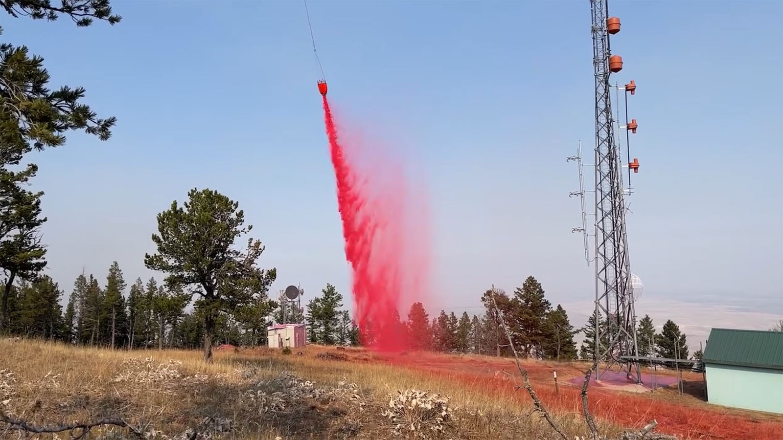 A bucket of retardant dangling from a helicopter is used to drop product onto the Elk Fire.