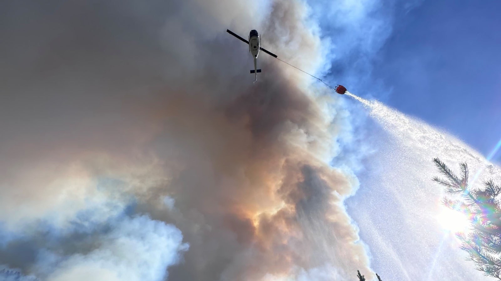 A helicopter drops a bucket of water on the Elk Fire.