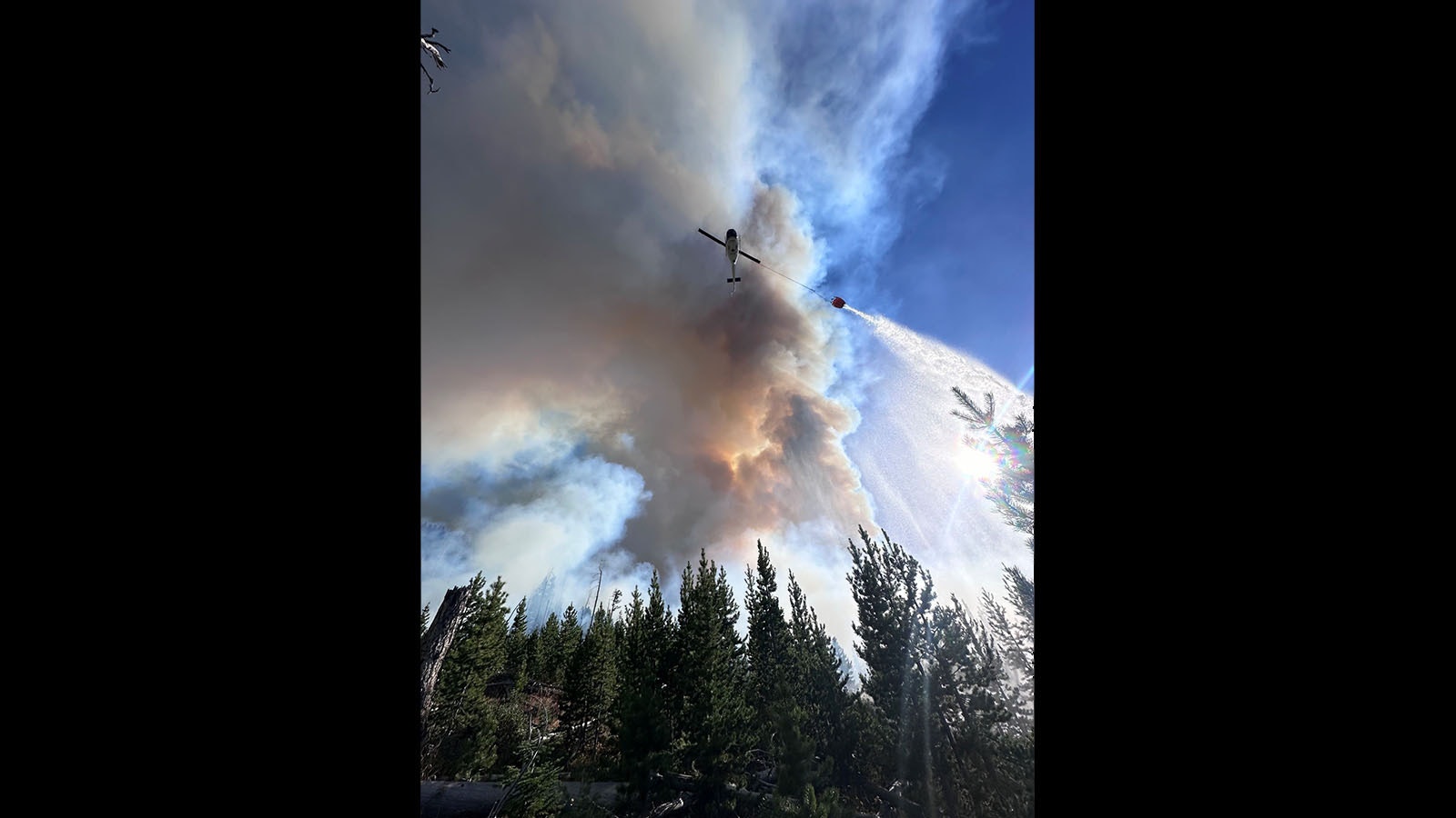 A helicopter drops a bucket of water on the Elk Fire.