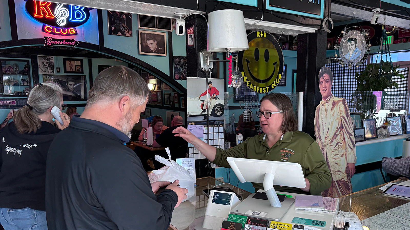 R&B Breakfast Club owner Valerie Martin works the register during a packed rush, with Elvis looking on from behind.
