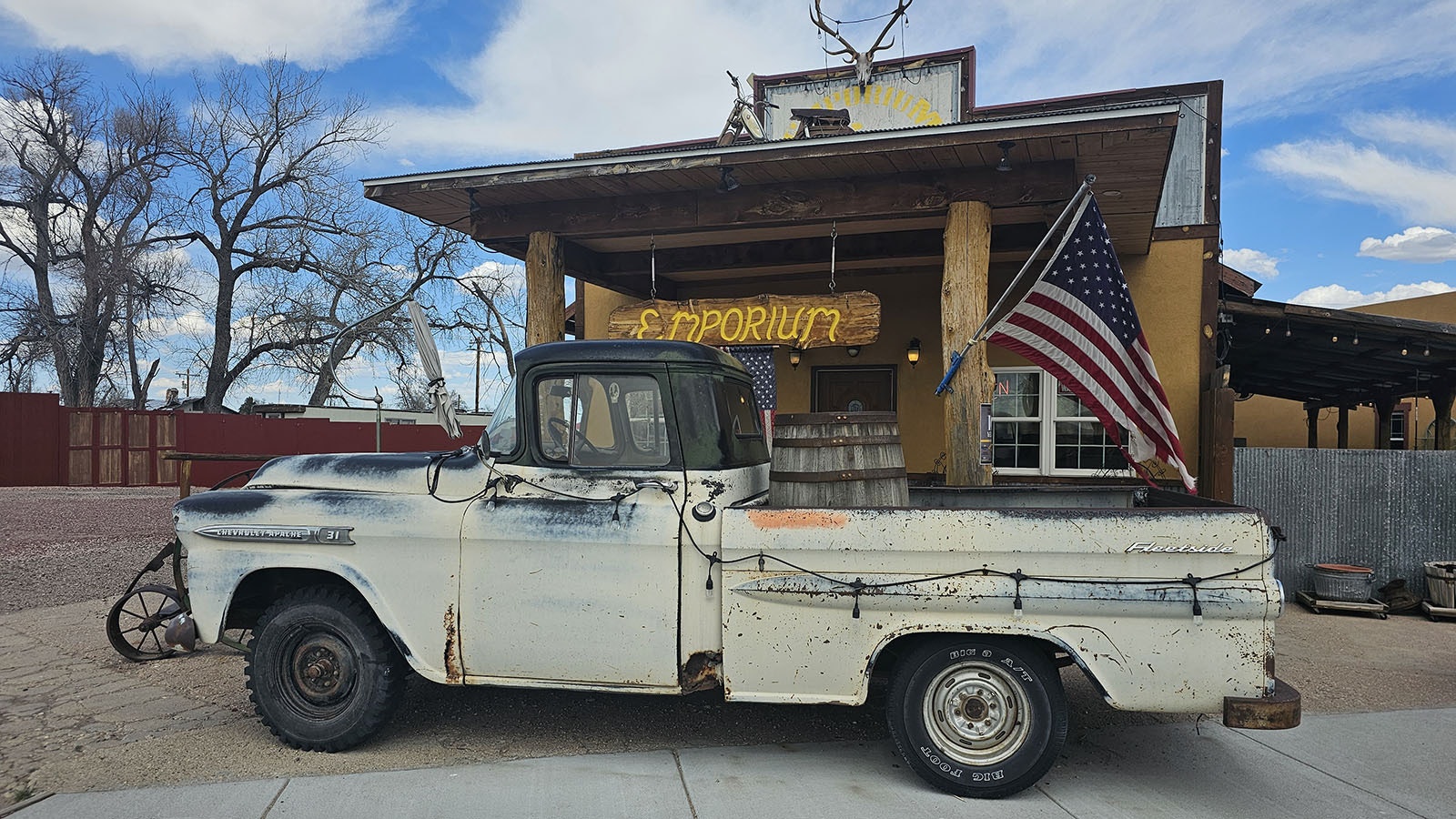 An old pickup truck with a beer keg in back is lighted up at night to draw attention to The Emporium.