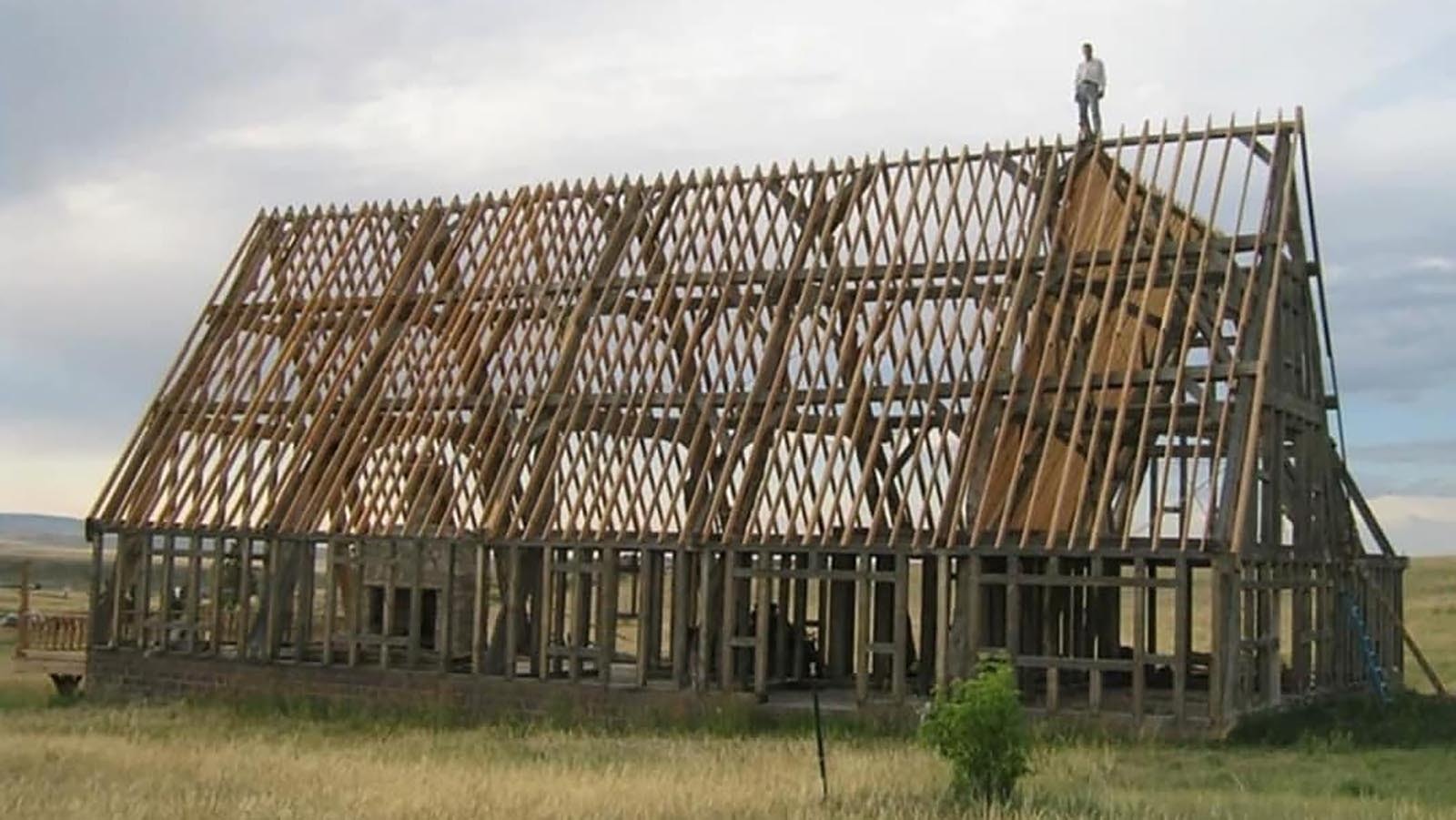 Cyning Meadowcroft standing atop the central portion of his home patterened after a medieval mead hall.