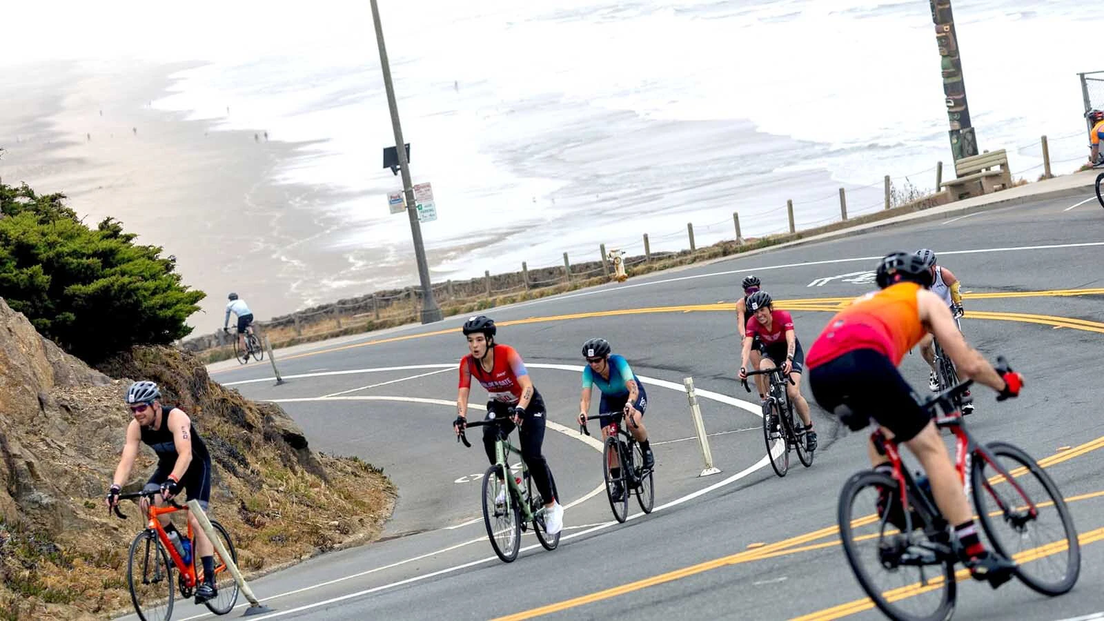 Cyclists from a past triathlon tackle a hill by the ocean.