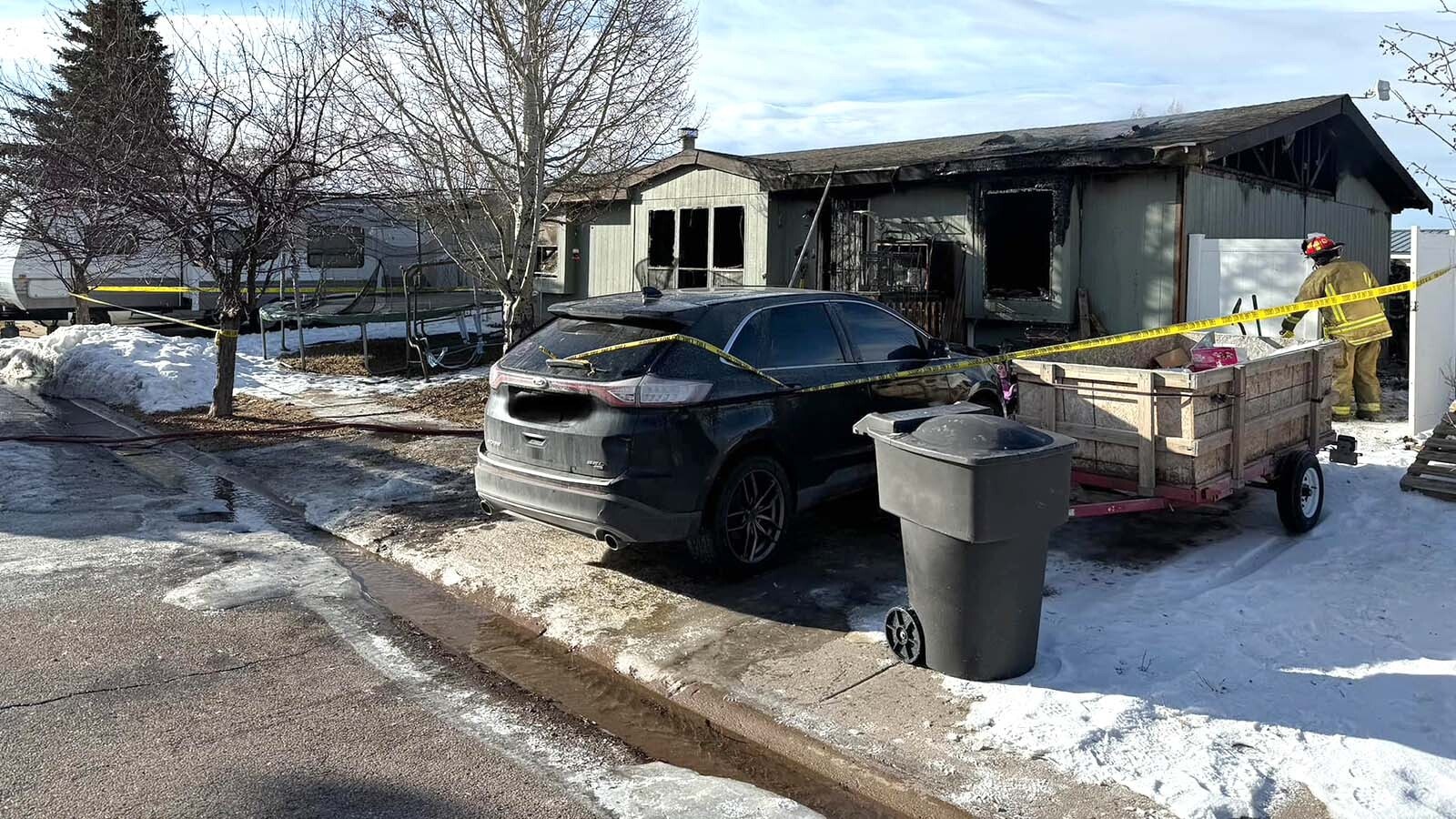 A Uinta County firefighter cleans up Saturday after an early morning fire in this mobile home on Worland Circle in Evanston that claimed the lives of two children, ages 6 and 3, and an adult family member.