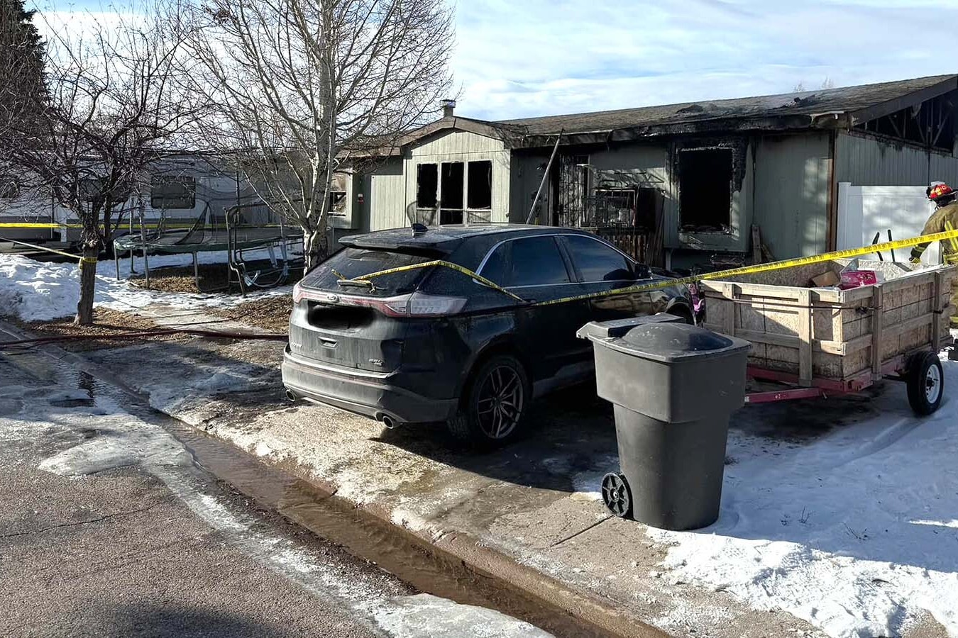 A Uinta County firefighter cleans up Saturday after an early morning fire in this mobile home on Worland Circle in Evanston that claimed the lives of two children, ages 6 and 3, and an adult family member.