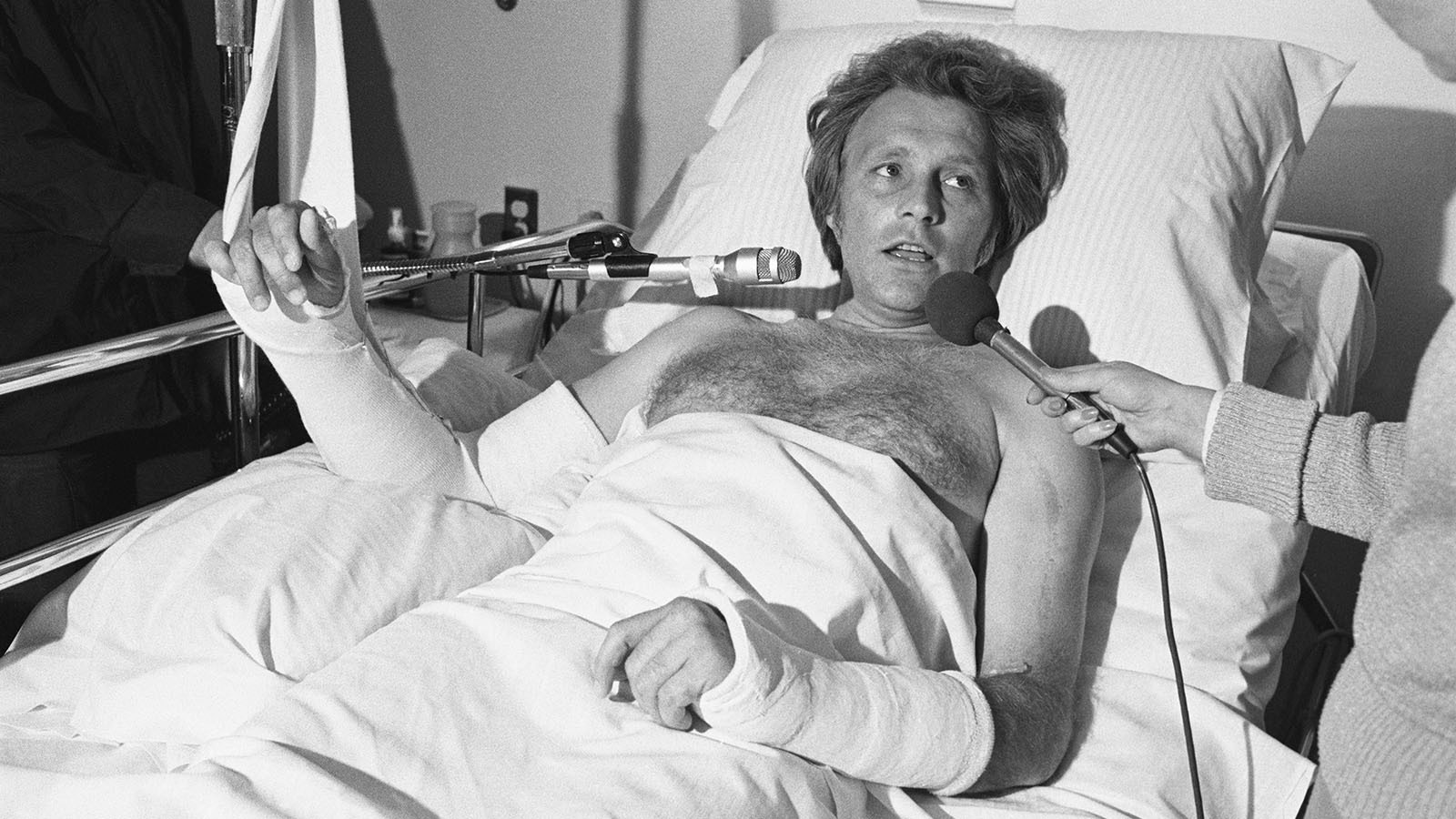 Evel Knievel gives interviews from a hospital bed after losing control on the landing after clearing a pool of sharks.