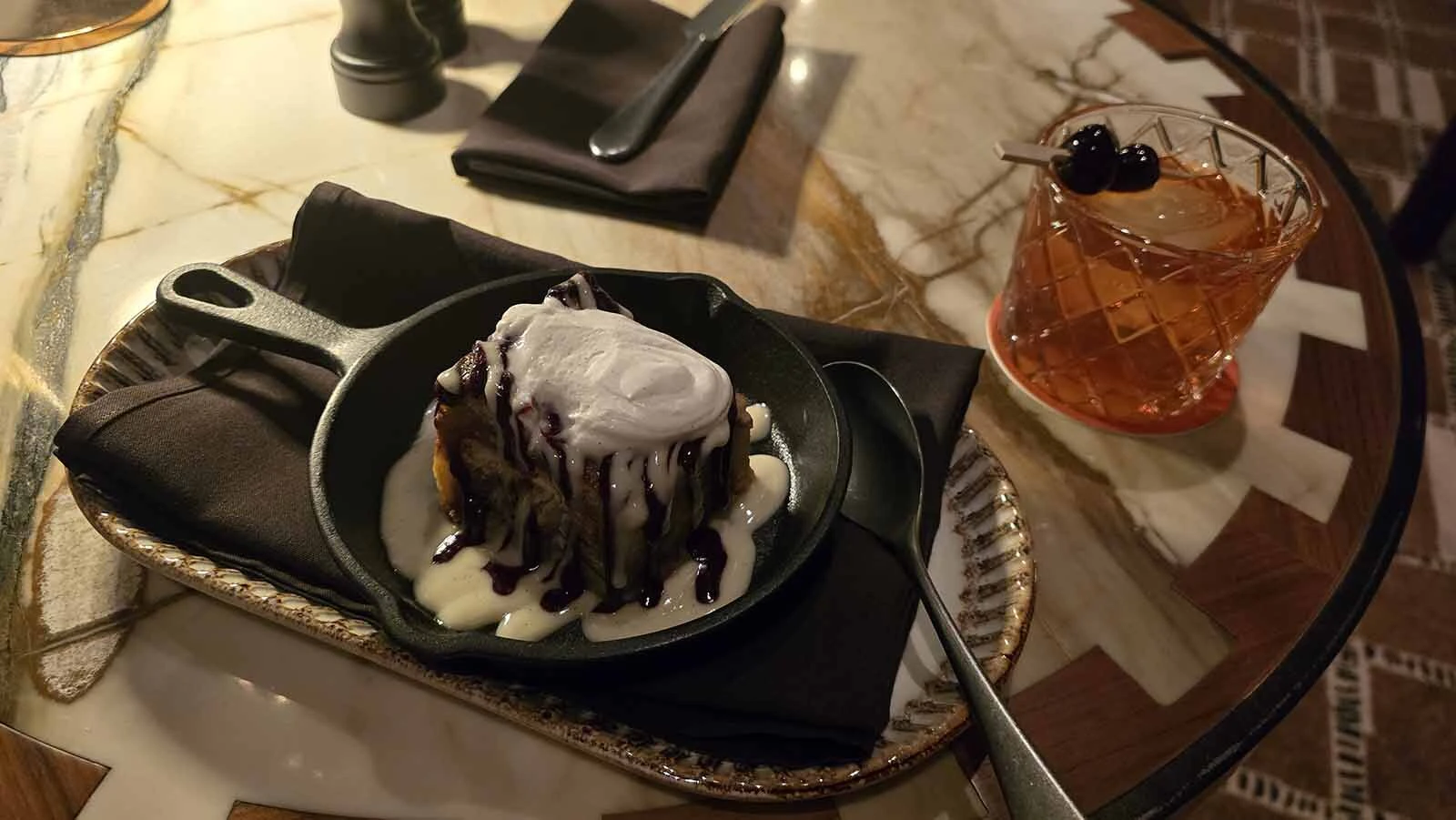 Desserts and cocktails are also available, like this bread pudding with berry sauce and whipped cream, paired with a classic old-fashioned.