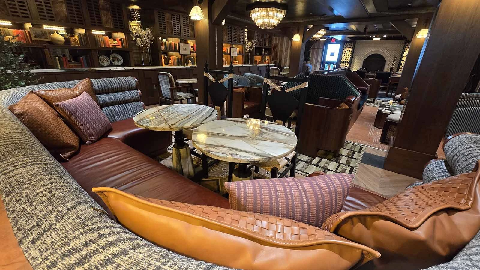 The back lobby area has been reimagined as a living room, complete with a small curated library of books as well as a cozy fireplace. In the back, there’s a community table with modern charging ports.