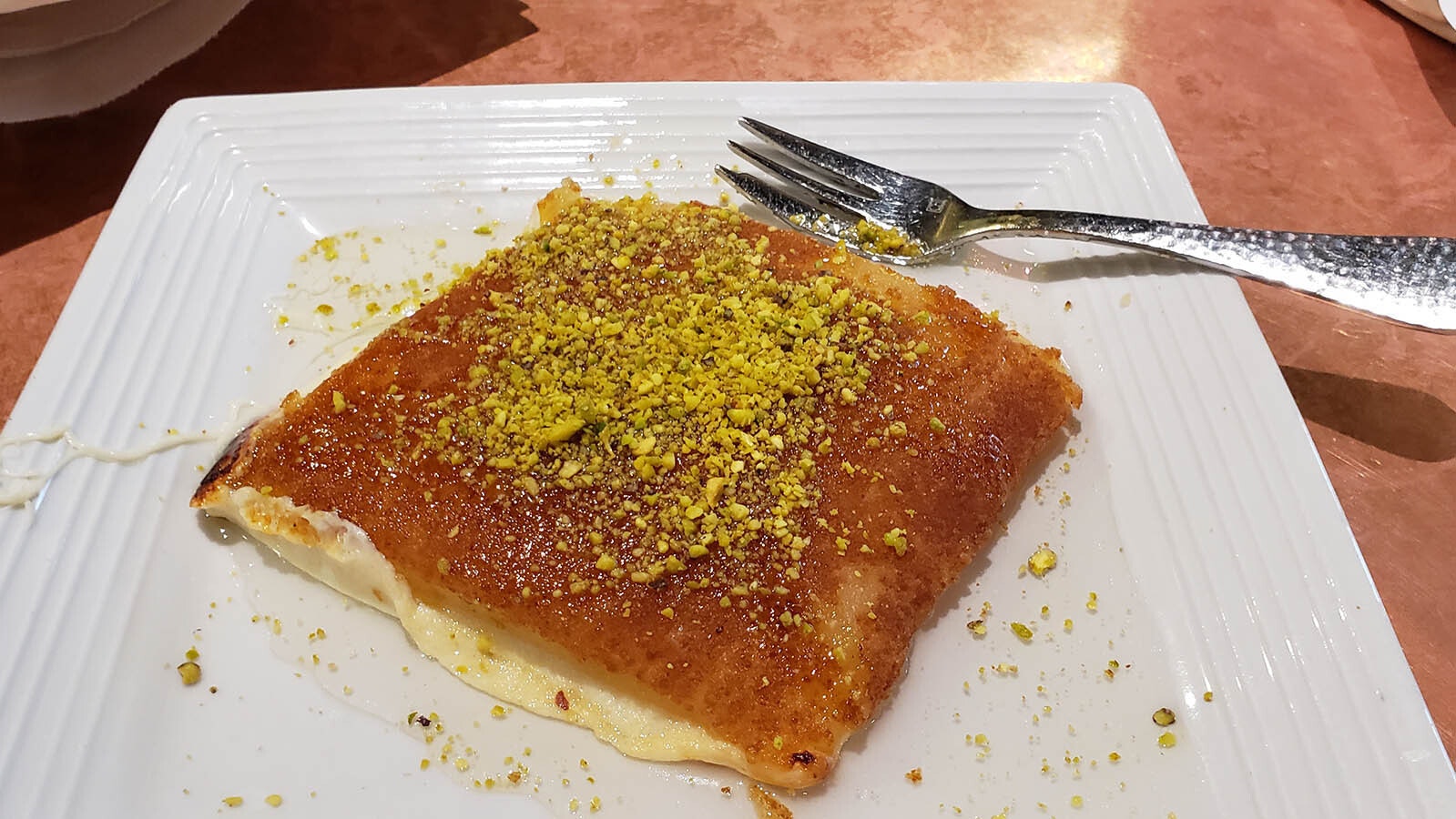 This dish is a Lebanese cheesecake known as knafeh (pronounced kanayafeh). This can be eaten for breakfast, but at figs it's available as a dessert. It's a toasted stringy mozzarella-like cheese topped with rose syrup and nuts.