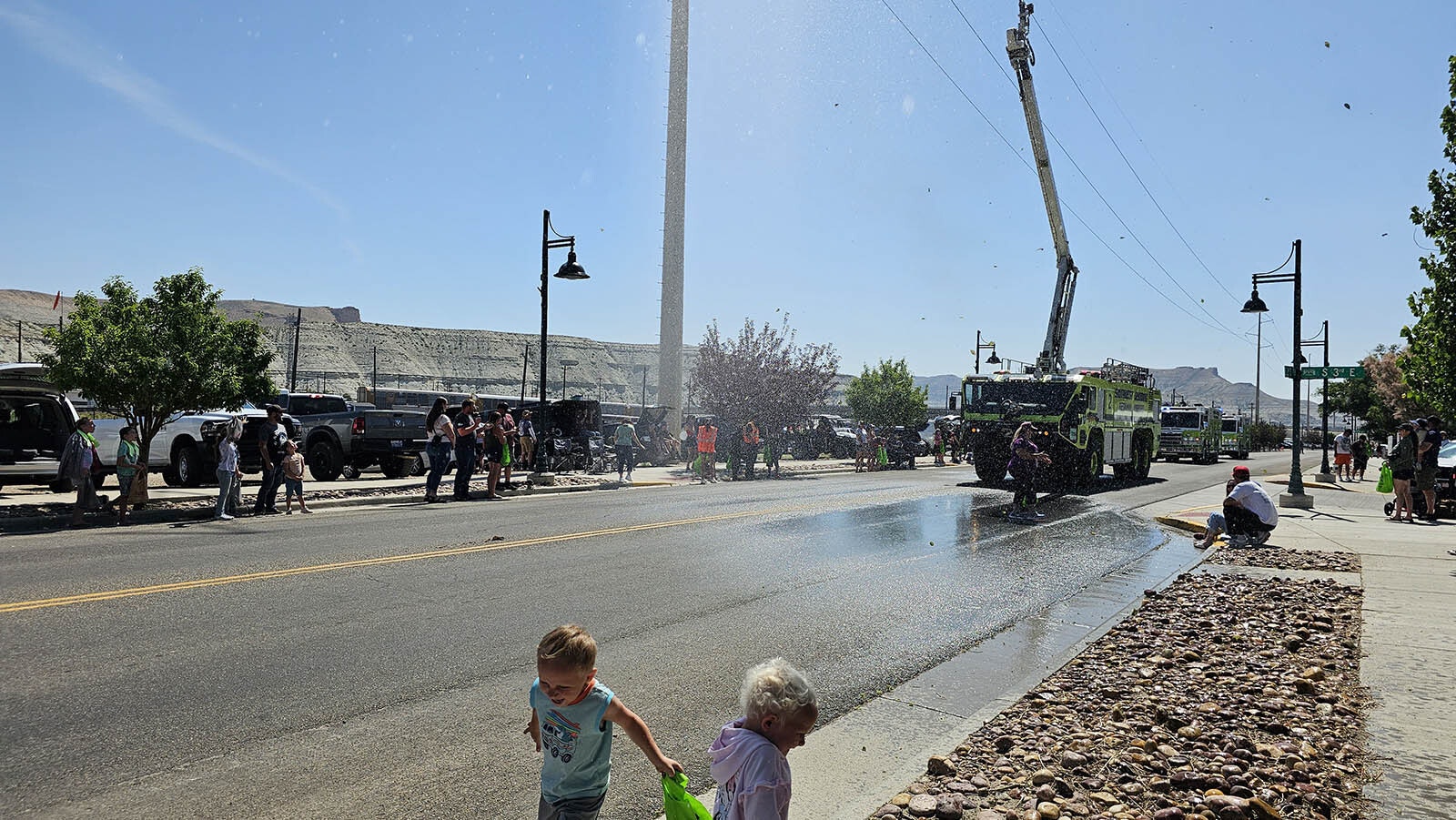 Everly and Logan Smith run away from the oncoming firetruck to avoid getting wet. Then they rush back out to pick up a couple of pieces of candy once it has gone past.