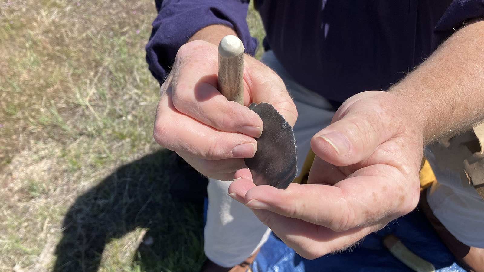 Jim Shipley holds up a flake of rock that is extremely sharp. When light can pass through the edge, the rock is like a scalpel.