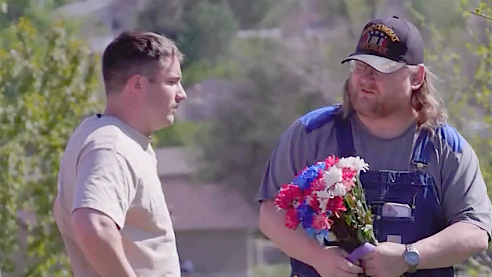 Matthew Hohnholt holds flowers for his son’s grave presented to him by Samuel Weidehofer. Hohnholt’s son committed suicide last year and Hohnholt is trying to pay off the funeral debt.