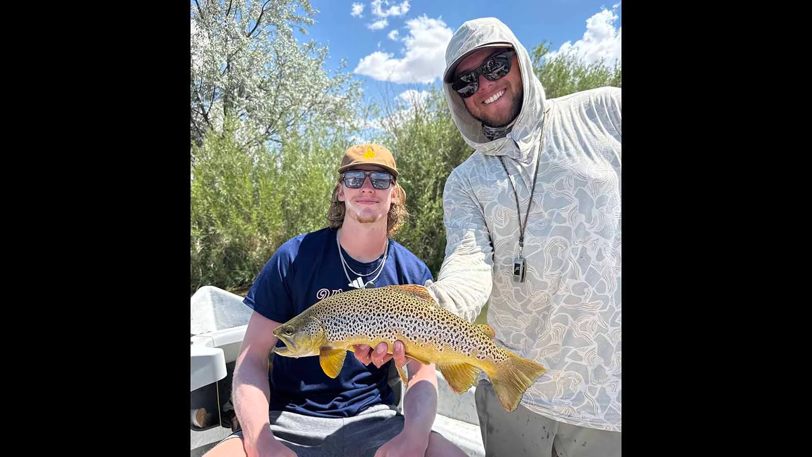 University of Wyoming basketball player Gavin Gores, left, and fishing guide Jarom Brown hold up a brown trout Gores caught.