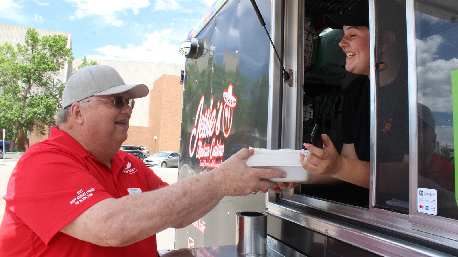 Cheyenne resident Tim Bolin receives his green chili burger from Jessie's Mexican Cuisine food truck worker Lexi Fehlberg.