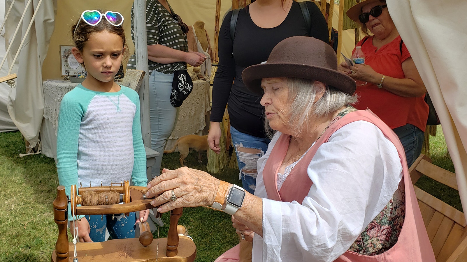Melinda Barlow demonstrates spinning to a child passing by her tent in Trader's Row at the Fort Bridger Rendezvous.