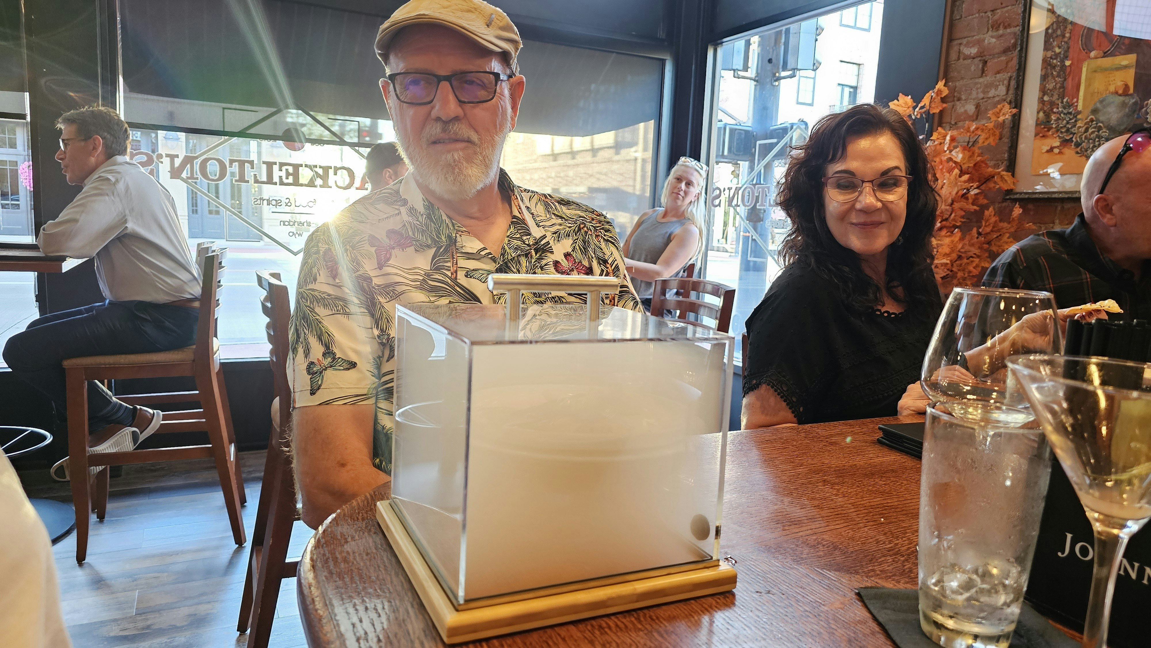 A customer waits on smoke to penetrate his smoky Manhattan, while other customers in the bar look on.