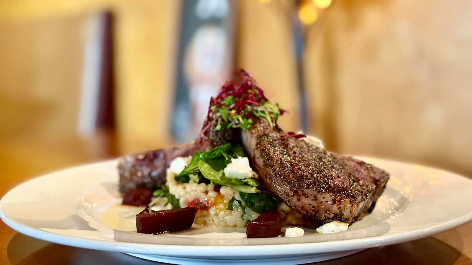 Sườn cừu ăn kèm couscous nướng, minh chứng cho chất lượng ẩm thực tại Frackelton's, nơi phục vụ cả sheridan cocktails độc đáo.