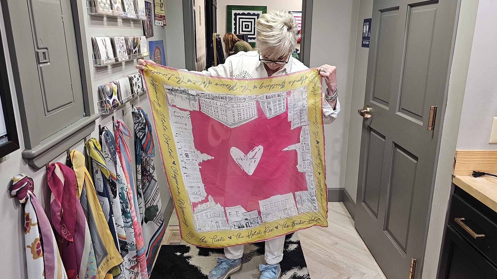 Bel Henrich, a cashier at the boutique store Alexis Drake, holds up a scarf designed by the store's owner, Alexis Garrett.
