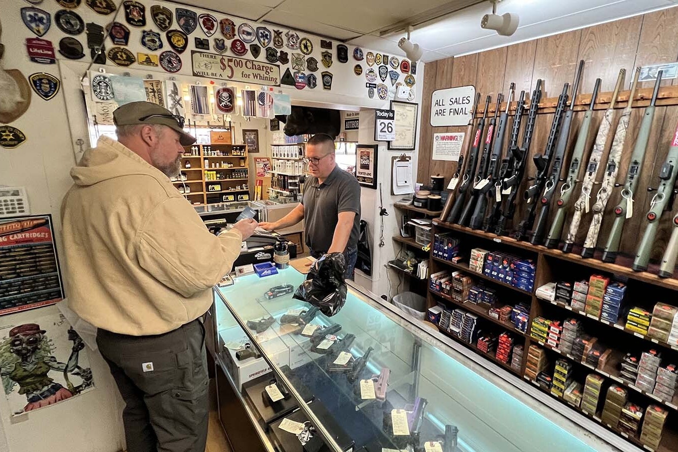 Frontier Arms and Supply owner Ryan Allen, right, conducts a credit card transaction with a customer Monday at the Cheyenne gun shop.