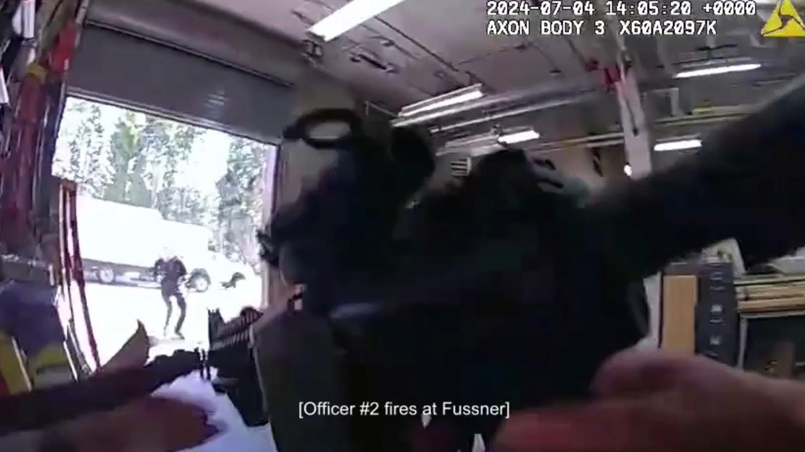 A still image from body camera video from officers involved in a July 4, 2024, shootout with Samson Fussner, a concessionaire worker who threatened a mass shooting. Fussner is seen in the background just as an officer fires at him.