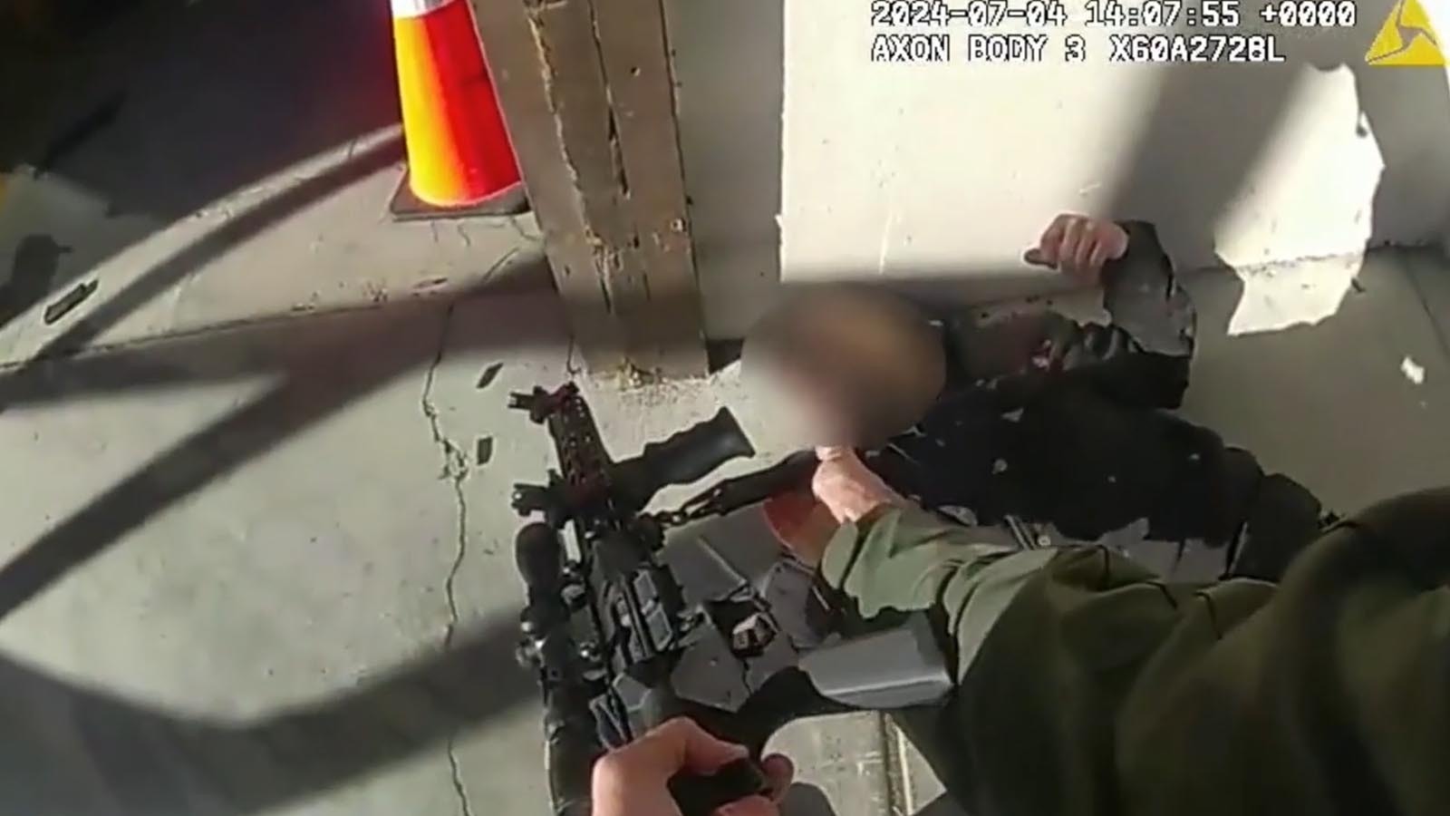 A still image from body camera video from officers involved in a July 4, 2024, shootout with Samson Fussner, a concessionaire worker who threatened a mass shooting. In this image, Fussner has been shot and an officer is removing the semi-automatic weapon he was wielding.