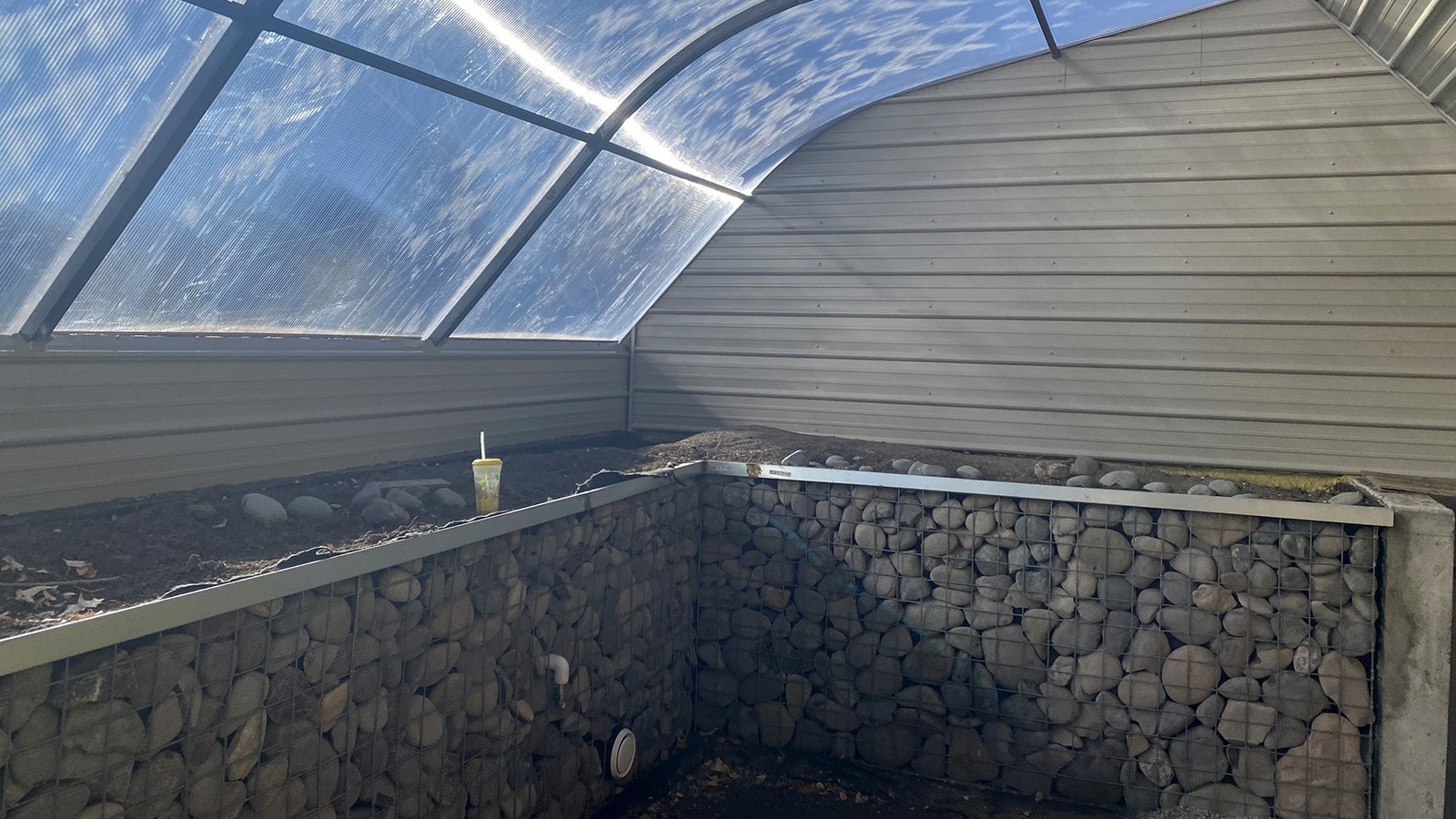 The geothermal greenhouse is built partly into the ground, with pipes delving 10-12 feet below the surface to tap into the earth's own natural thermostat to cool in summer and heat in winter.