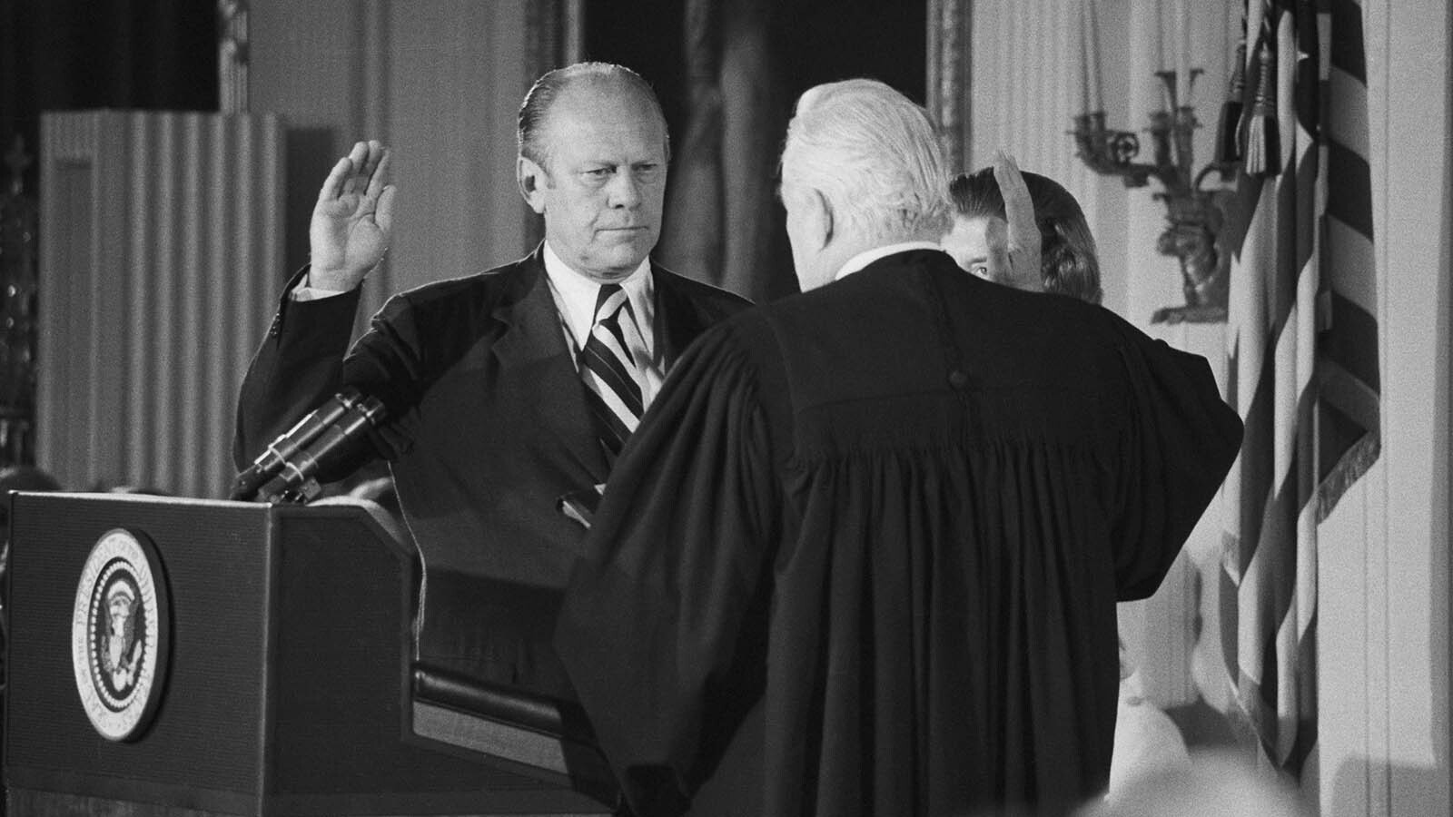 Gerald R. Ford takes the oath of office as the 38th President of the United States on Aug. 9, 1974. Chief Justice Warren Burger (in robes) administers the oath as Ford'd wife, Betty, (behind Justice Burger) looks on.