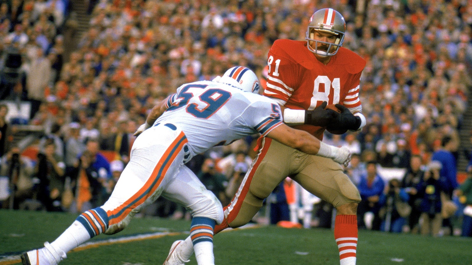 Russ Francis of the San Francisco 49ers, right, works to escape a tackle during Super Bowl XIX against the Miami Dolphins at Stanford Stadium on Jan. 20, 1985, in Stanford, California. The 49ers beat the Dolphins 38-16.