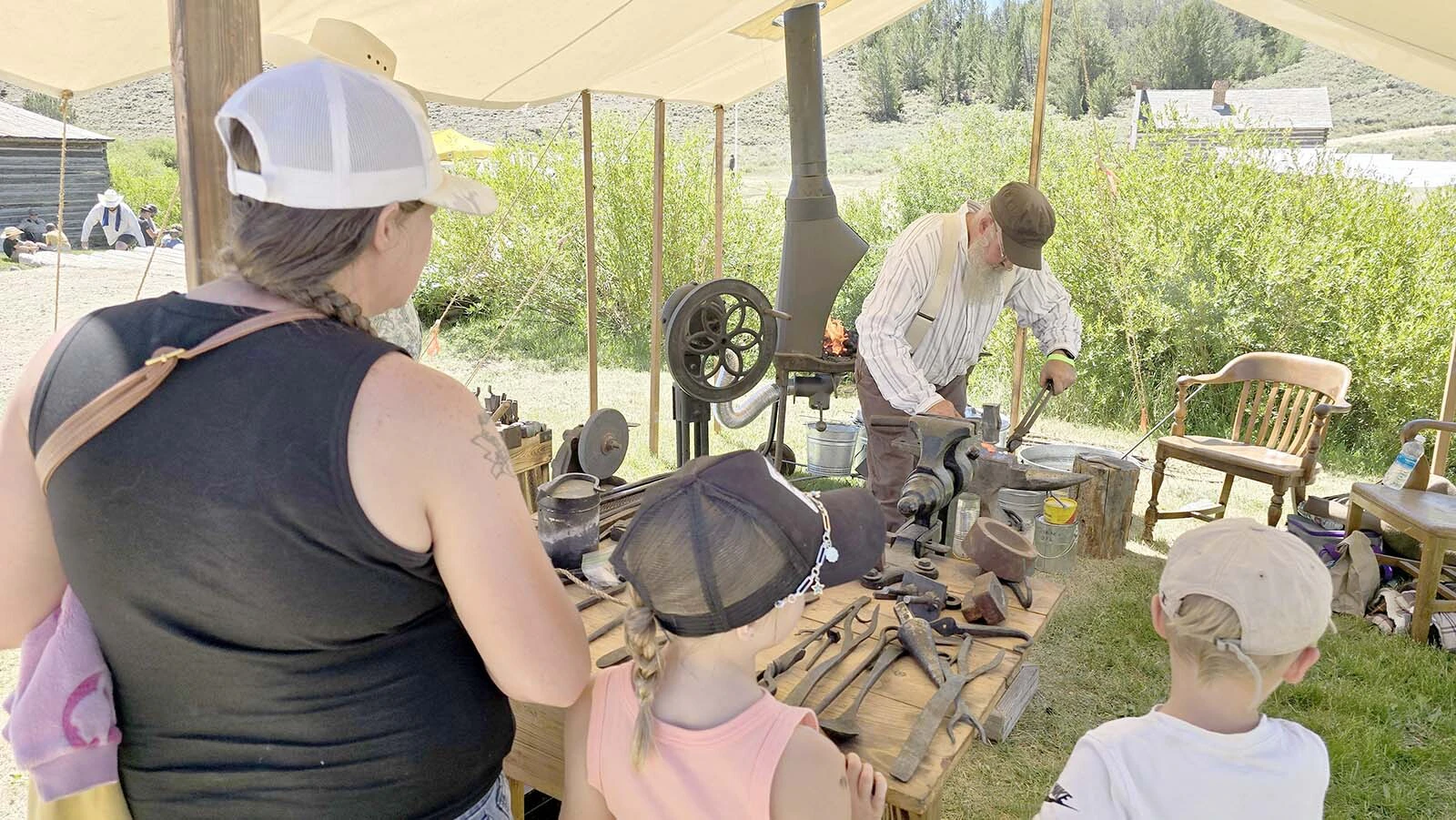 Guests watch as the blacksmith of South Pass City demonstrates the fine art of crafting metal tools back in the 1870s.