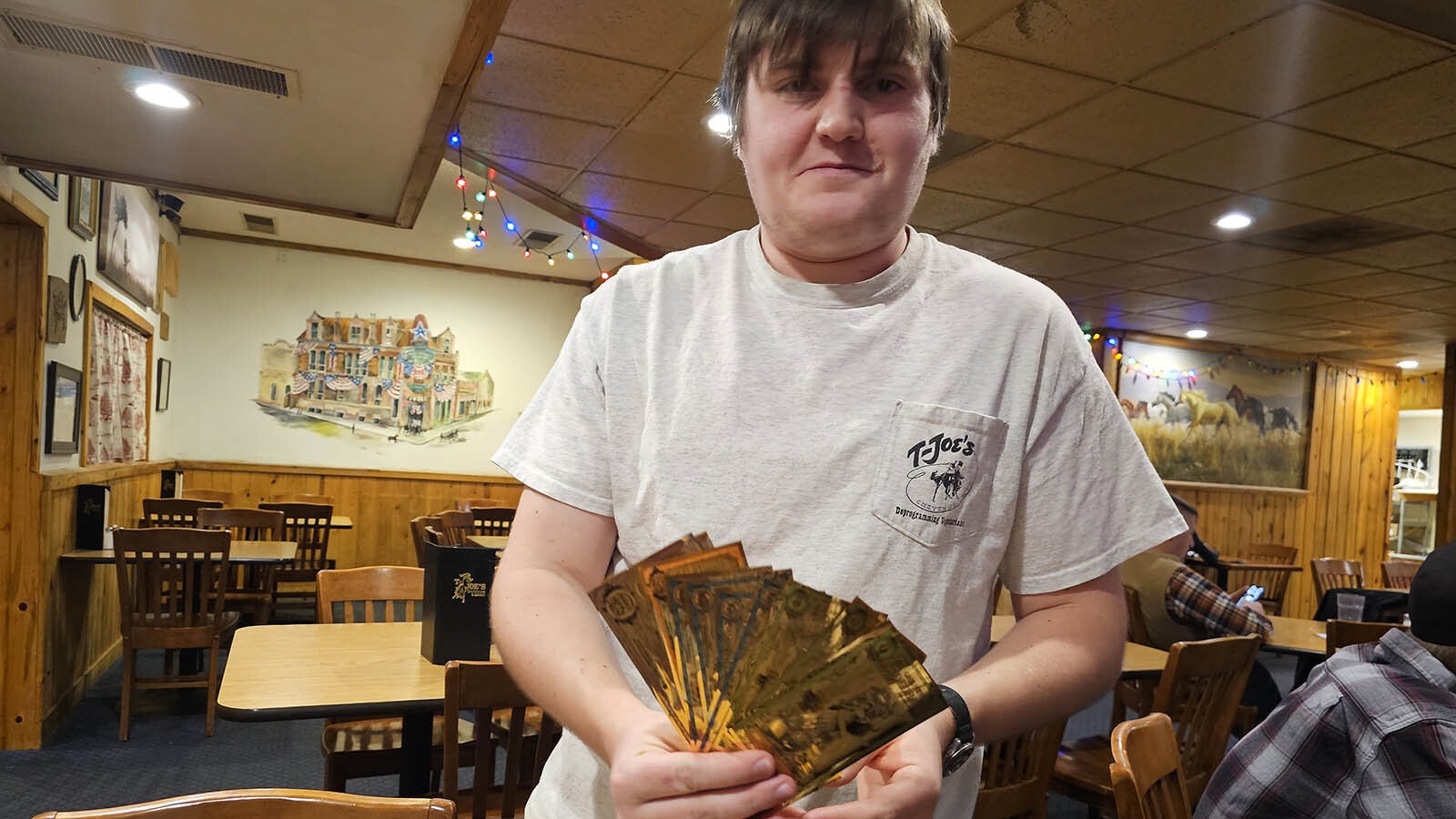 Jason "Junior" Lyle holds up a collection of goldbacks traded at T-Joe's Steakhouse and Saloon for meals. The restaurant is one of 160 stores in Wyoming that are willing to accept goldbacks in exchange for services.