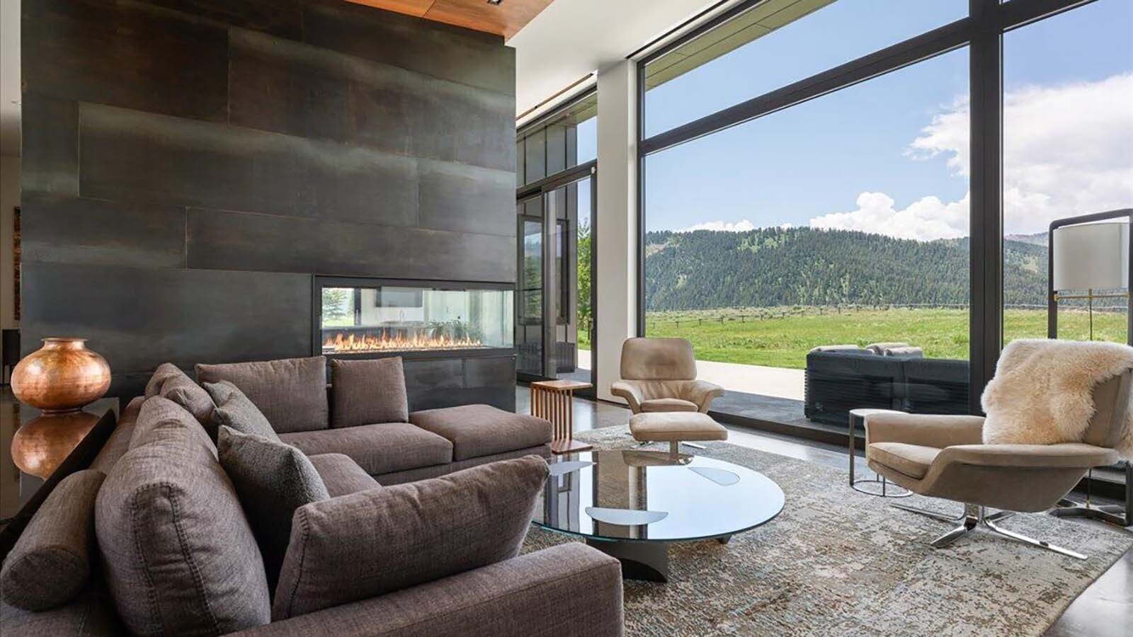 On the other side of the three-sided gas fireplace is a living room that looks out on a stunning view.