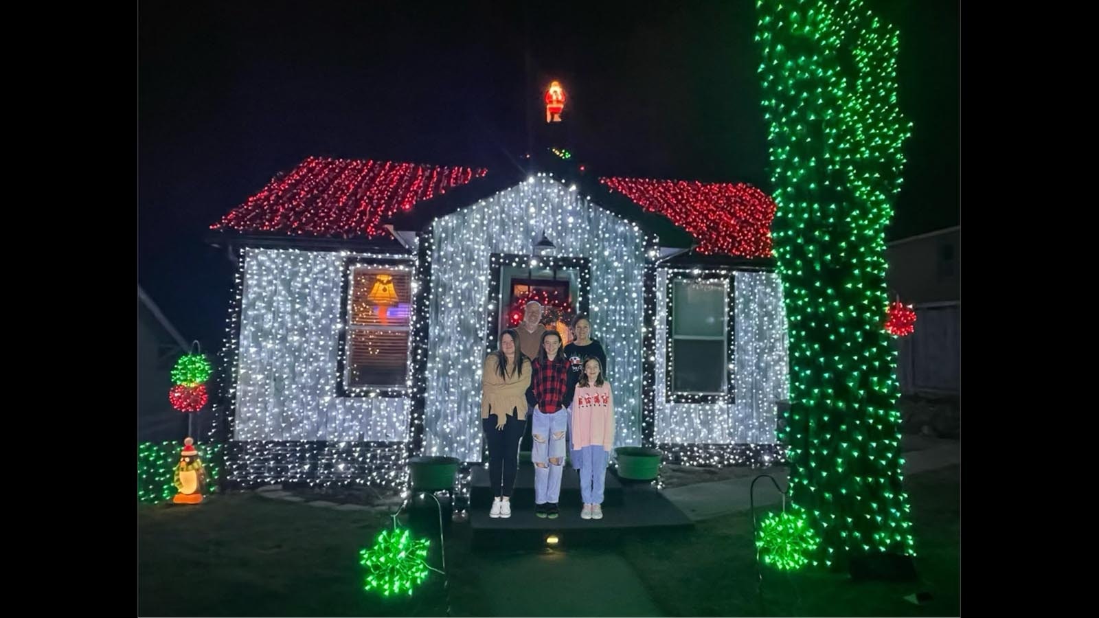 Ed and Kimberly Lambert with their daughters in front of their bright, festive home in Gillette.