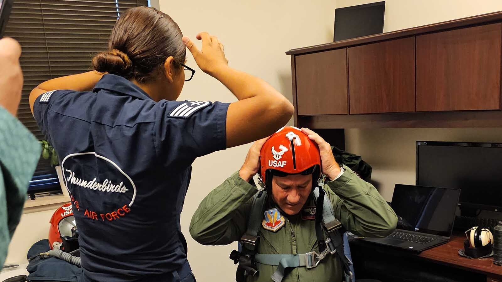 A member of the Thunderbirds team helps Brian "Alf" Grzegorczyk get his helmet fitted ahead of the Hometown Hero Flight on a Thunderbird F-16 Fighting Falcon model.